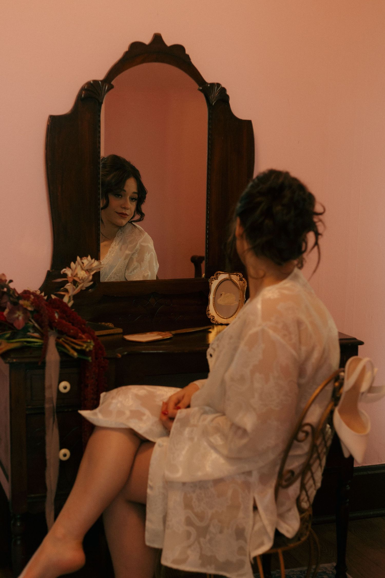 A vintage vanity scene with an ornate mirror reflecting soft lighting and lace details.