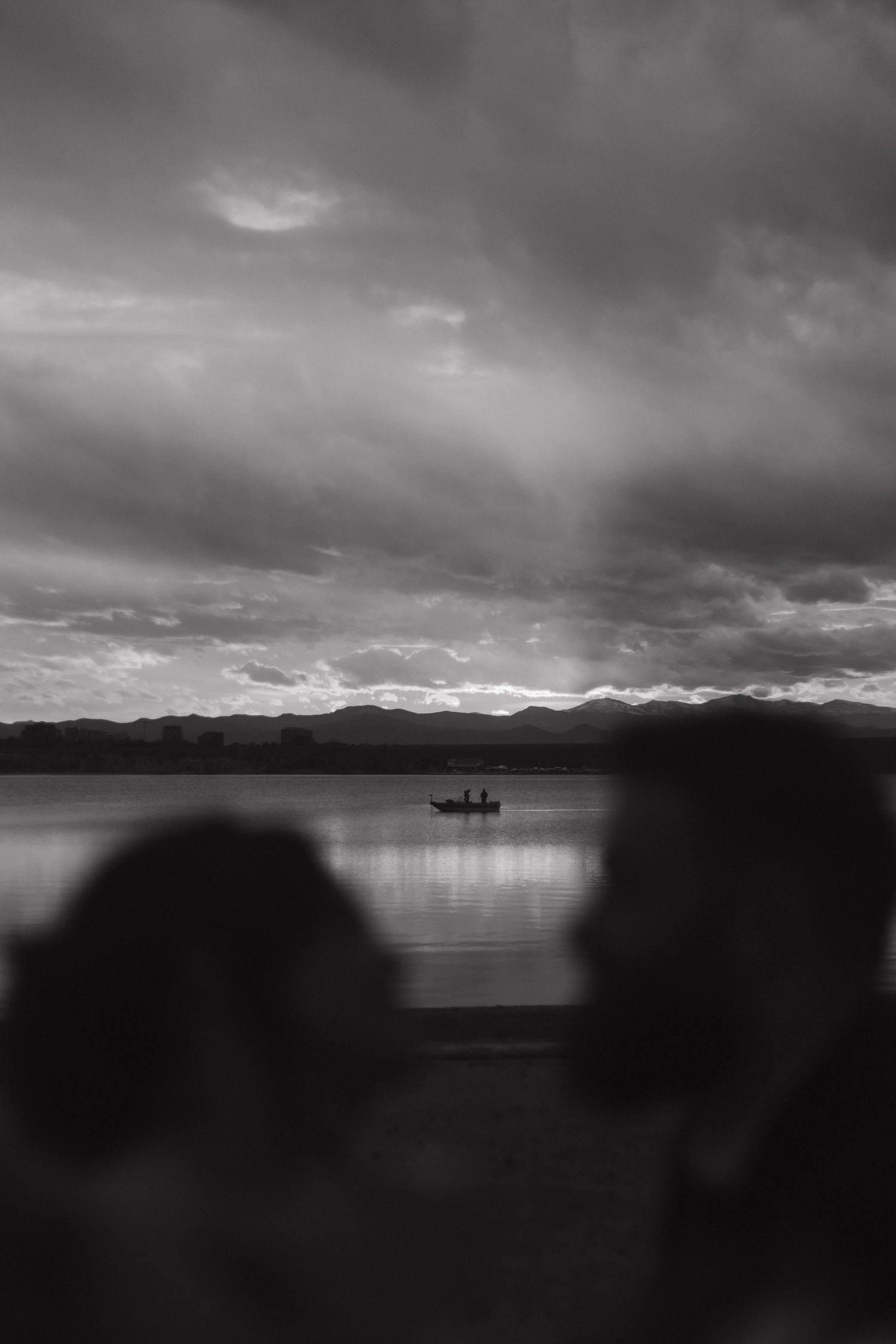 Dramatic black and white landscape of a lake with mountains and cloudy sky.