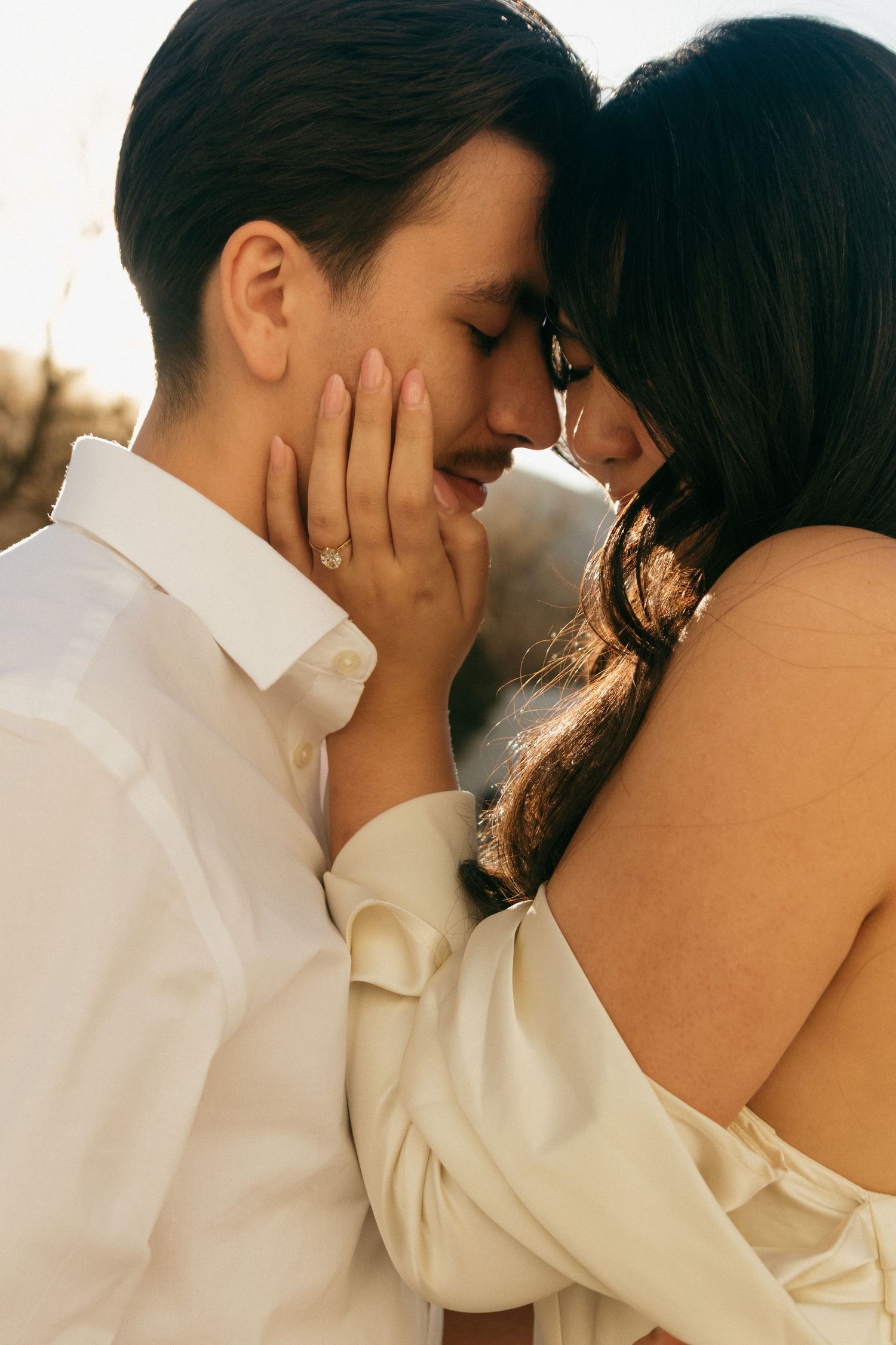 Intimate close-up shot of couple in white clothing during golden hour.