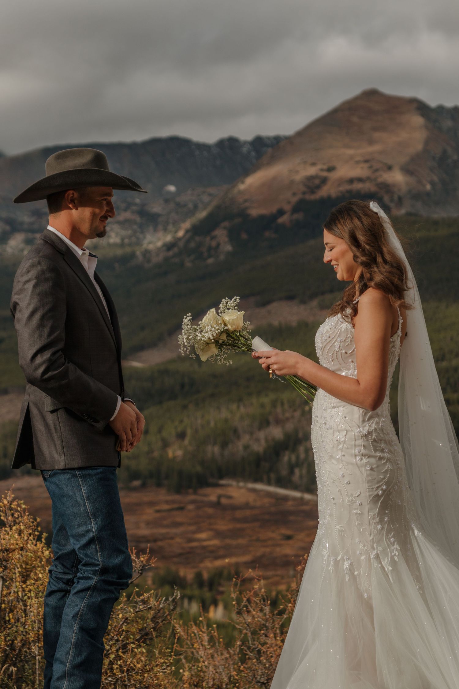A western-style wedding ceremony takes place against a dramatic mountain backdrop.