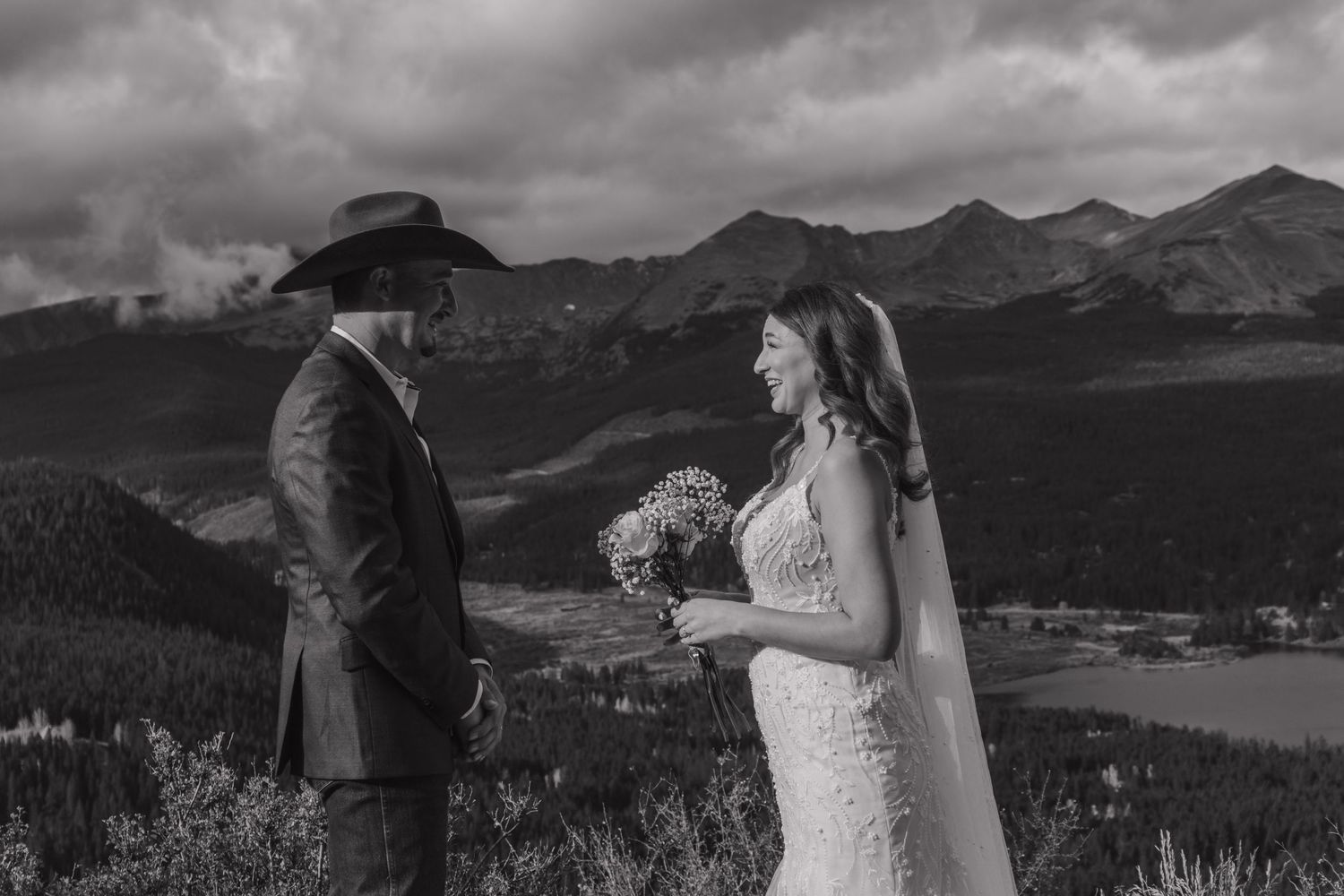 A scenic mountain wedding ceremony unfolds against dramatic cloudy skies and mountain peaks.