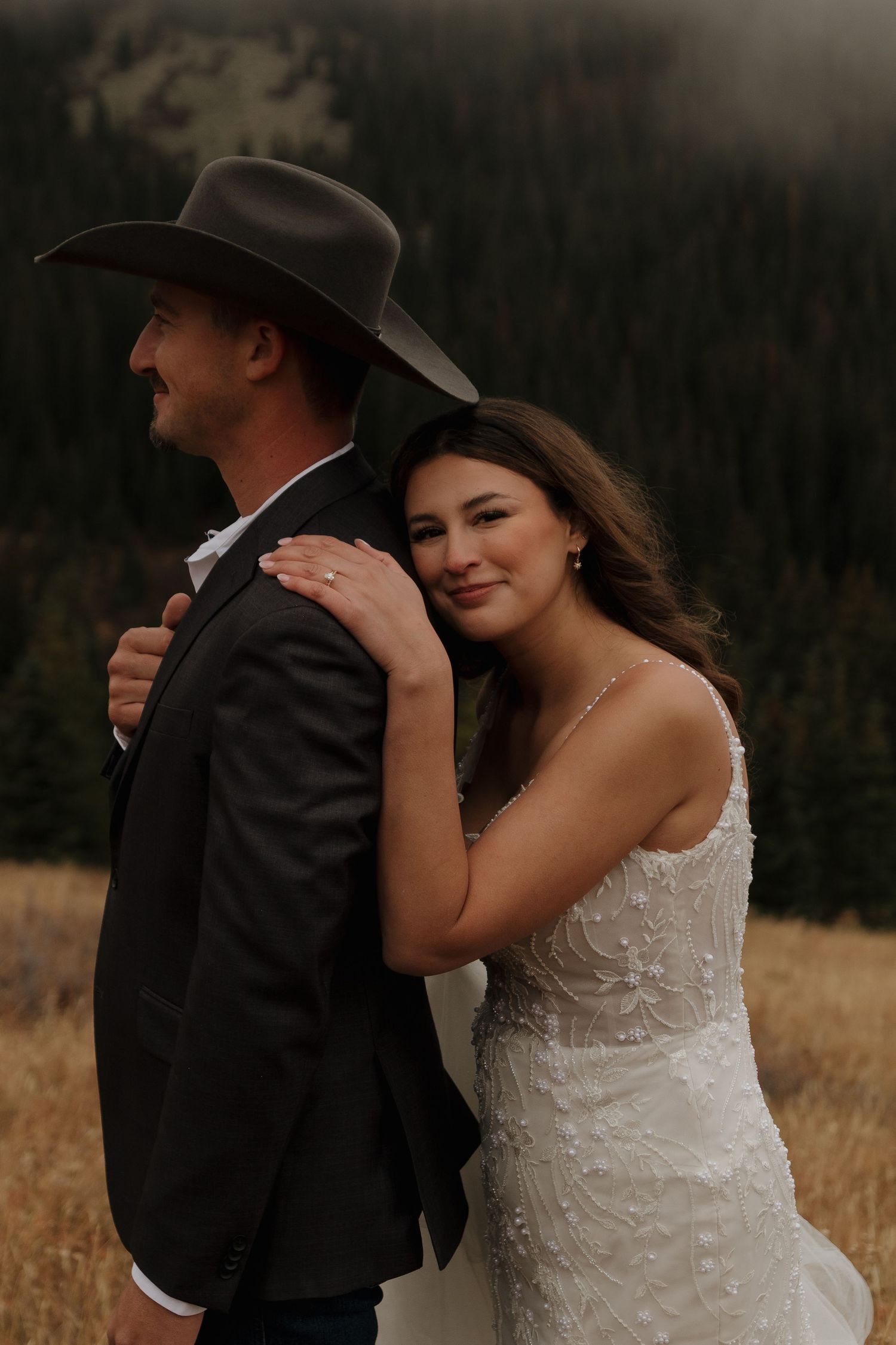 Romantic wedding photos show tender moments between newlyweds against a mountainous backdrop.