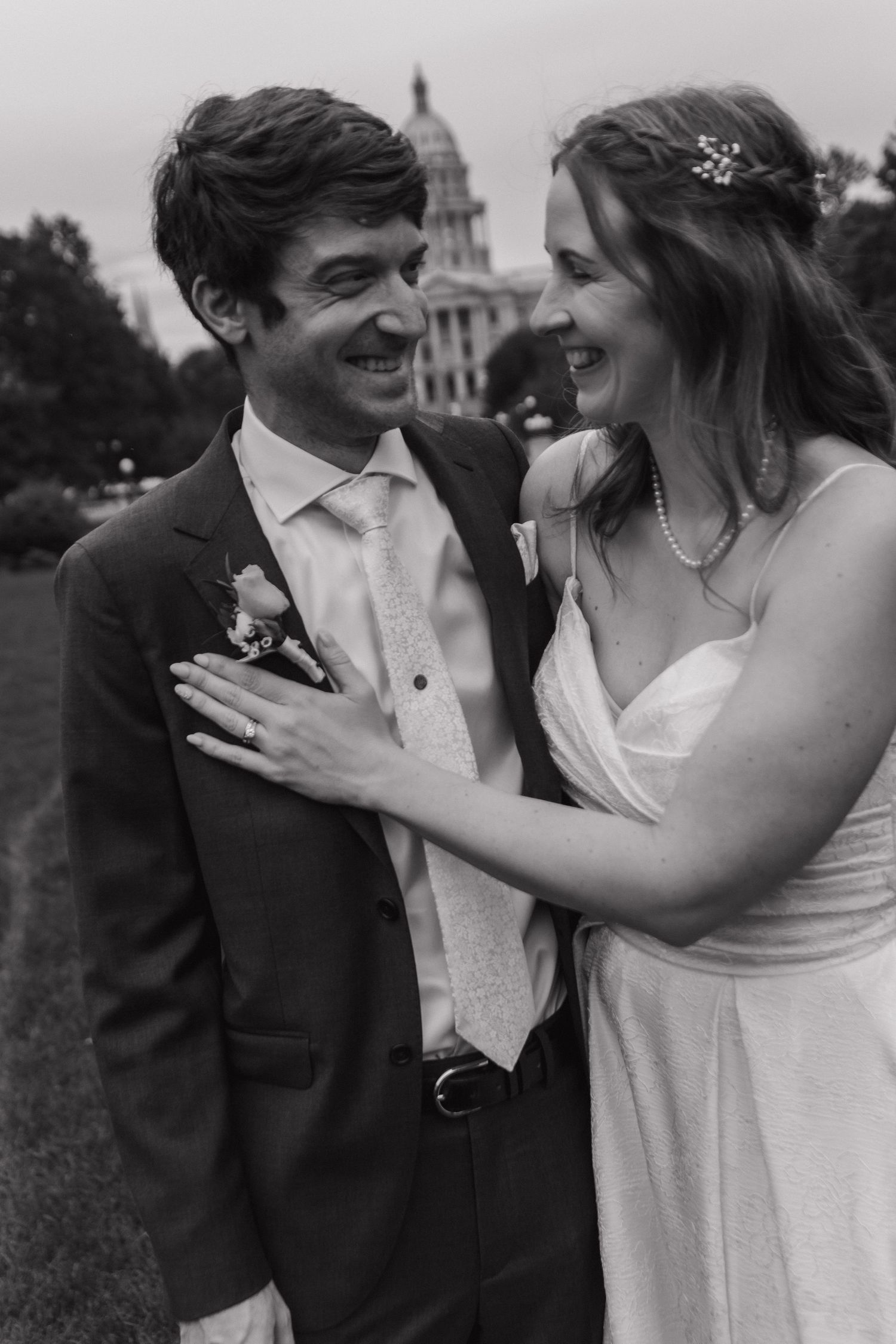 A series of black and white wedding photos showing a couple sharing joyful candid moments together outdoors.