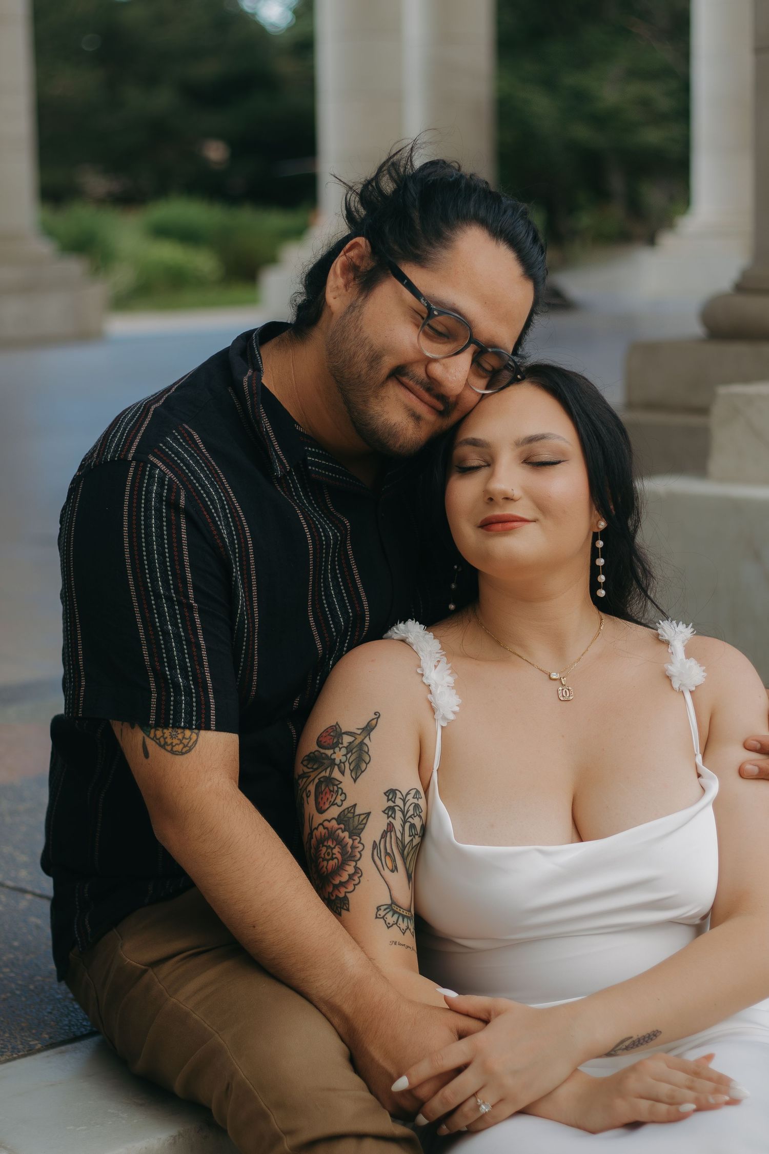 A couple shares an intimate moment while sitting together on marble steps outdoors.