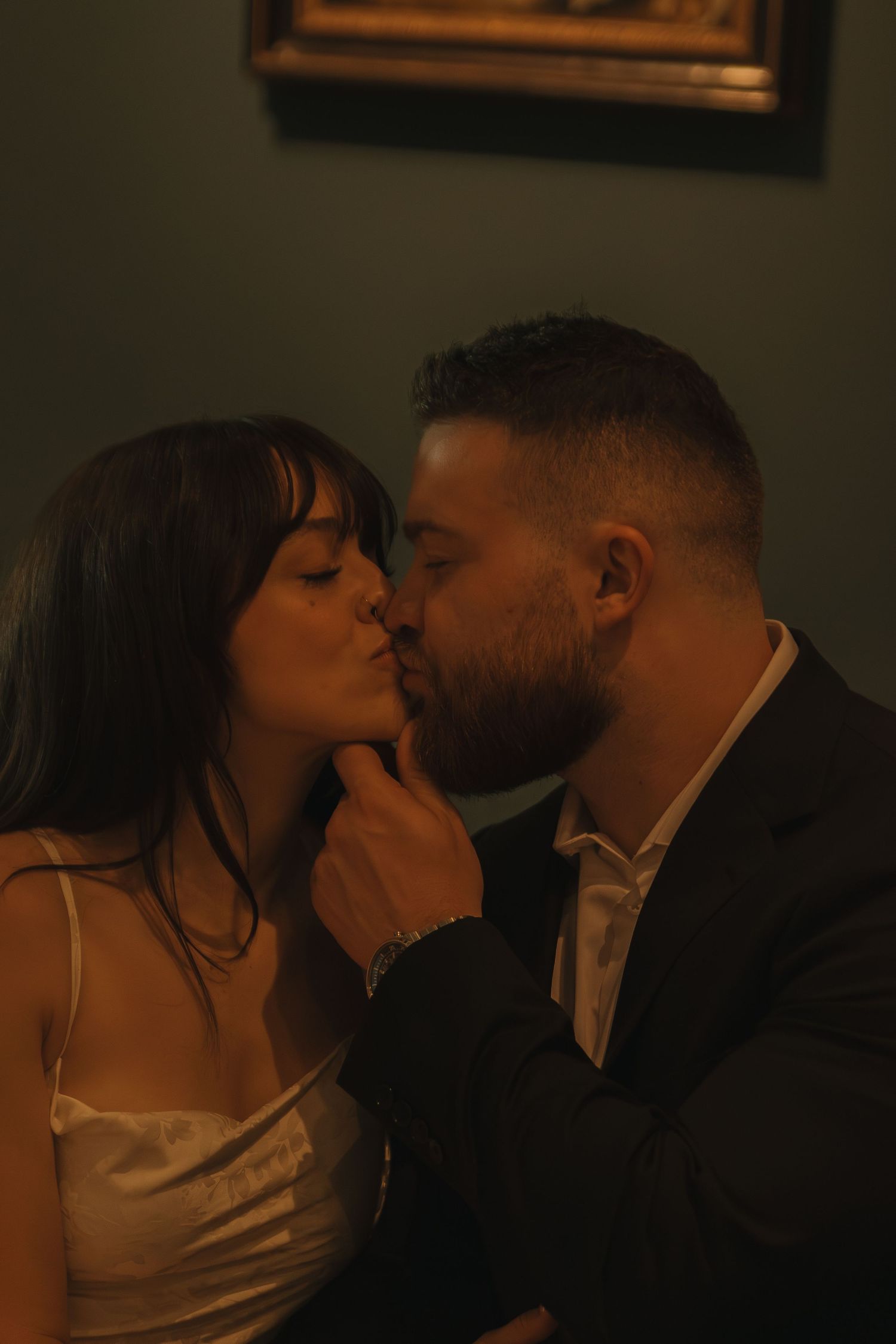 An intimate moment shared between two people in formal attire against a dark background.