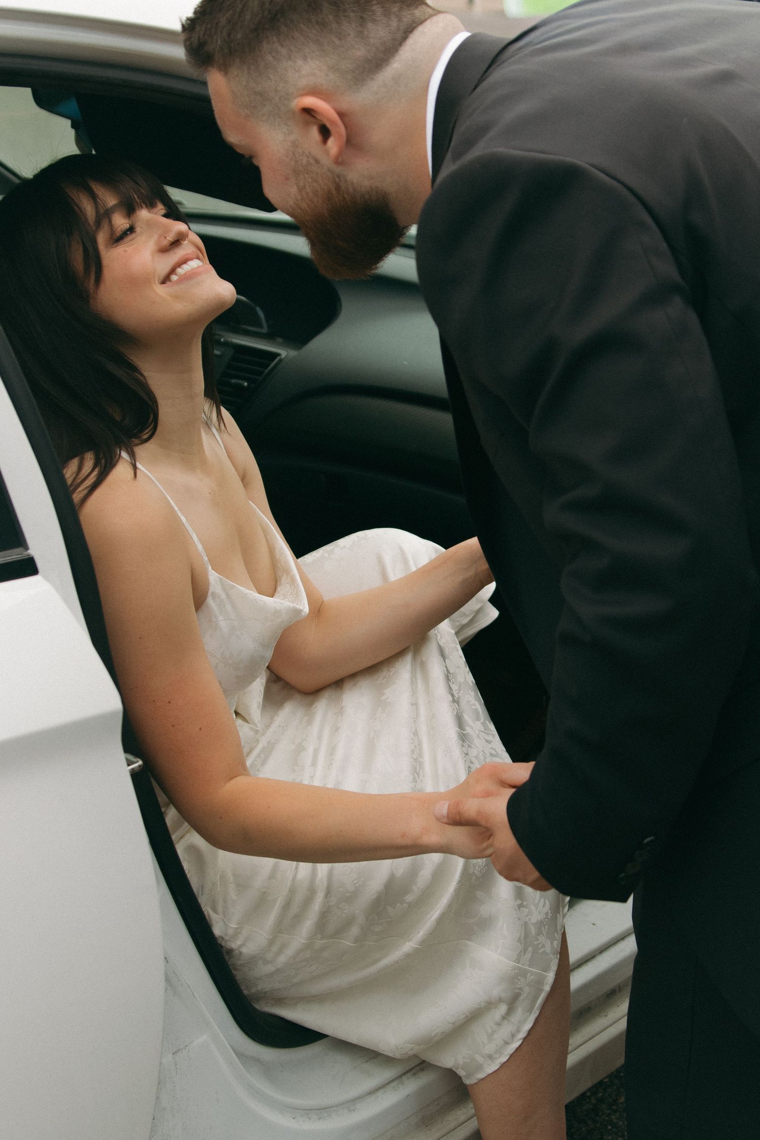 Romantic moment between a couple in formal attire near a vehicle.