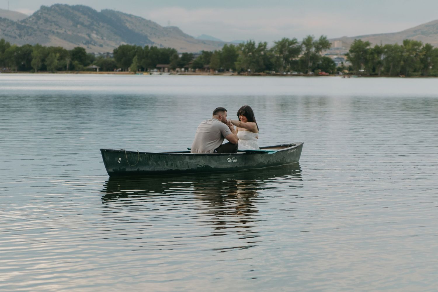 Scenic lake view with distant mountains and single canoe floating on calm waters.