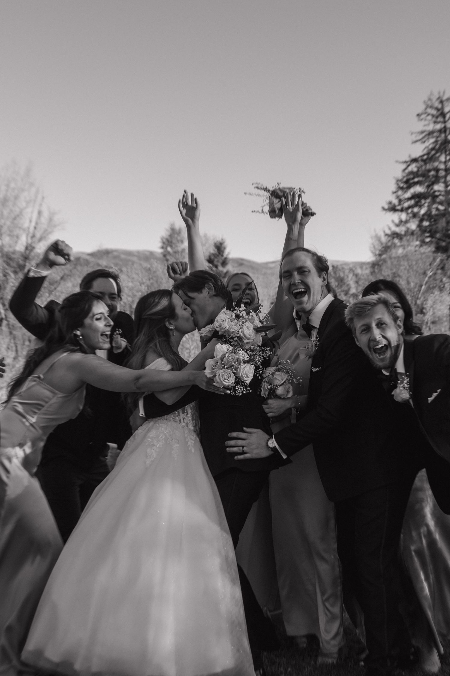 Wedding celebration with guests in formal attire posing energetically for a group photo.