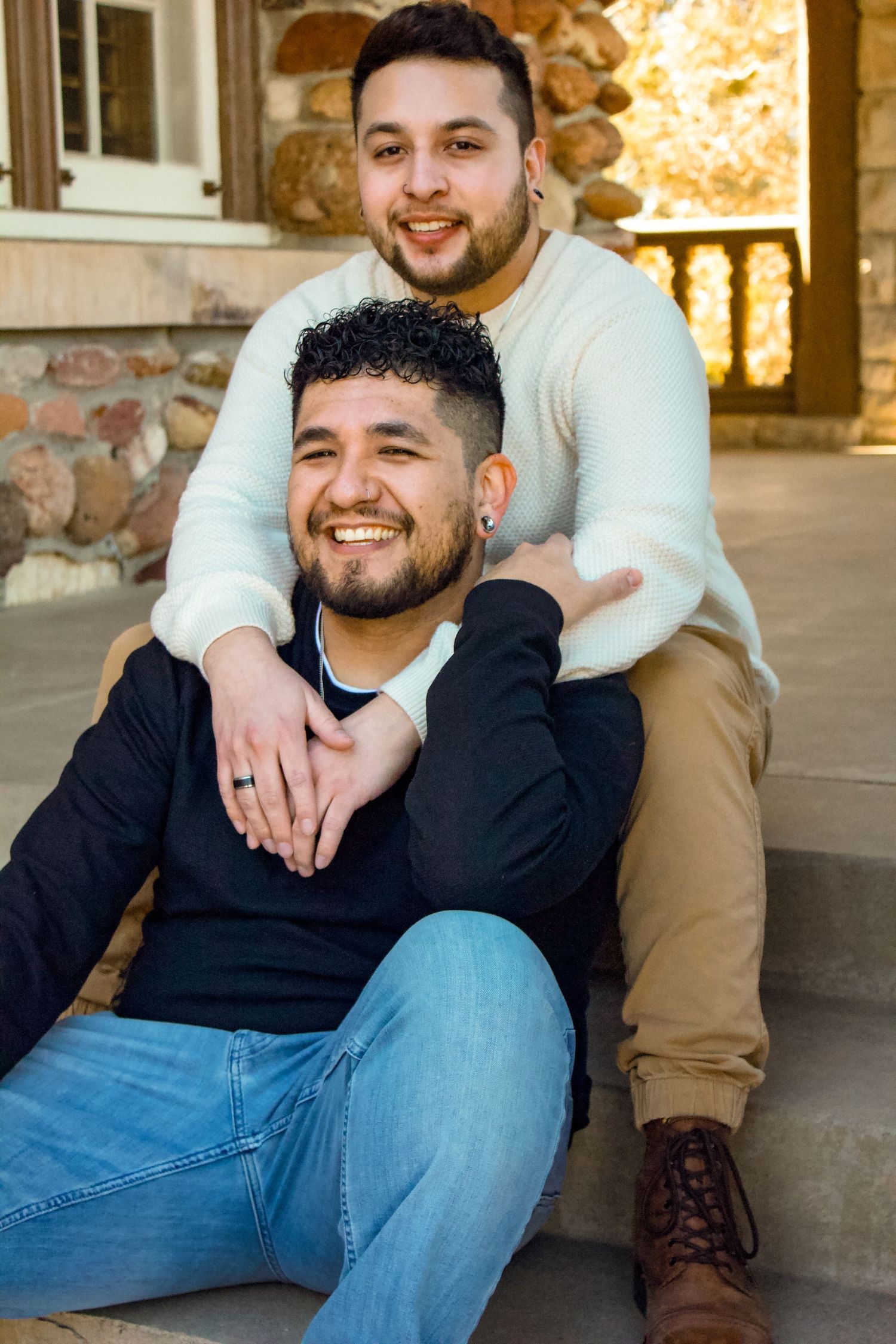 Couple posing on stone steps with warm lighting and rustic architecture.