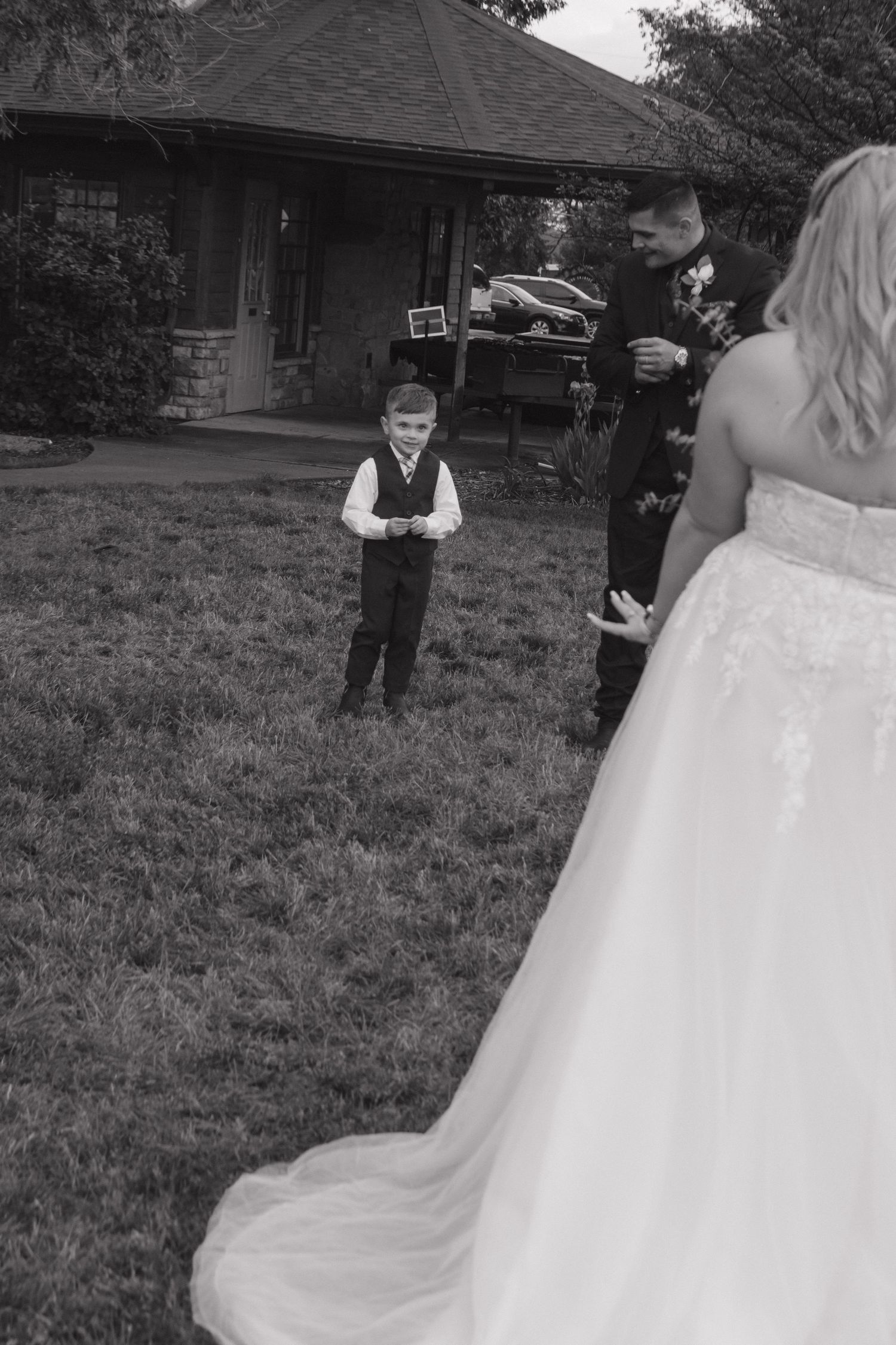 Black and white wedding photo showing the flow of a full white wedding gown outdoors.