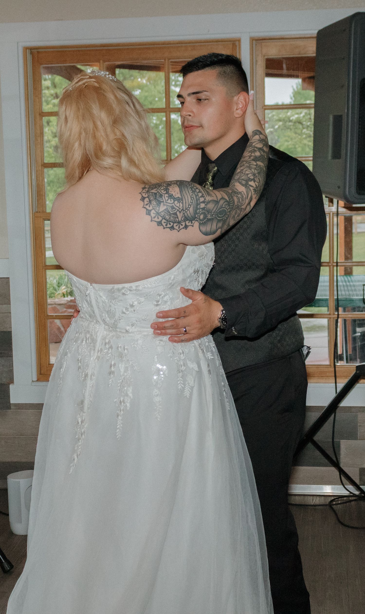 A couple dances together in an intimate moment near large windows in a reception venue.