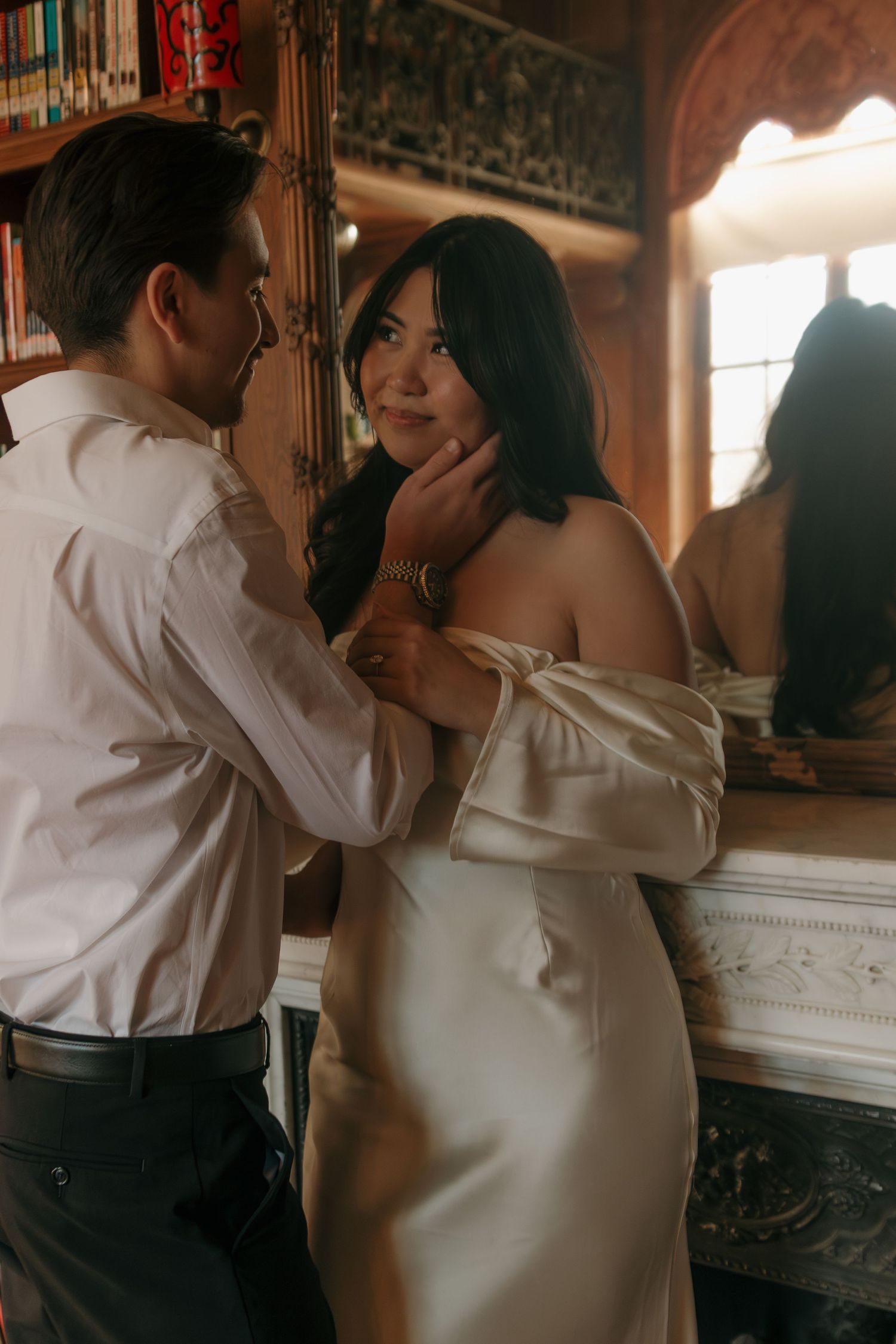 Intimate moment between a couple in formal attire against a library backdrop.