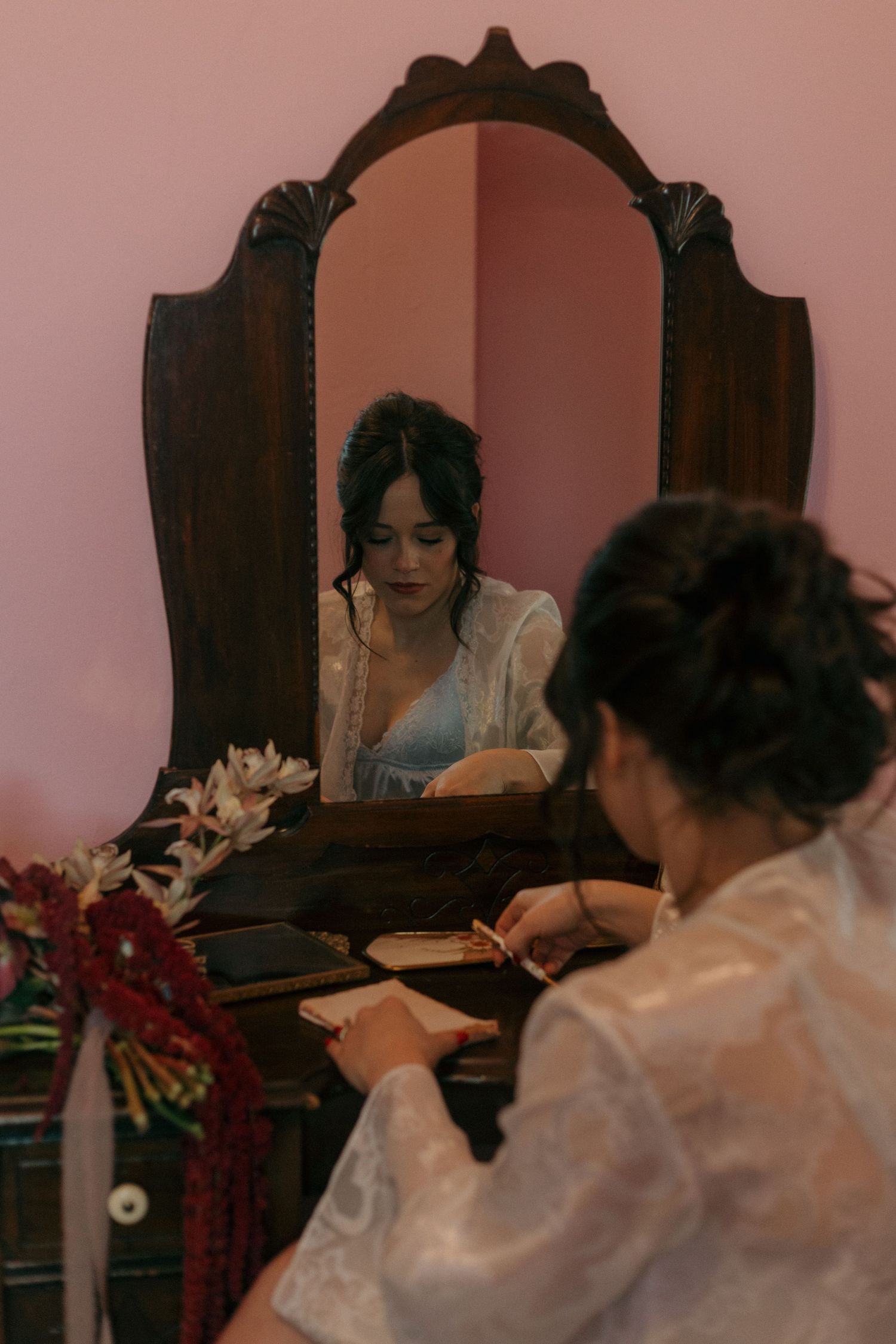 Wedding preparation scene with floral decorations and a vintage wooden vanity mirror.