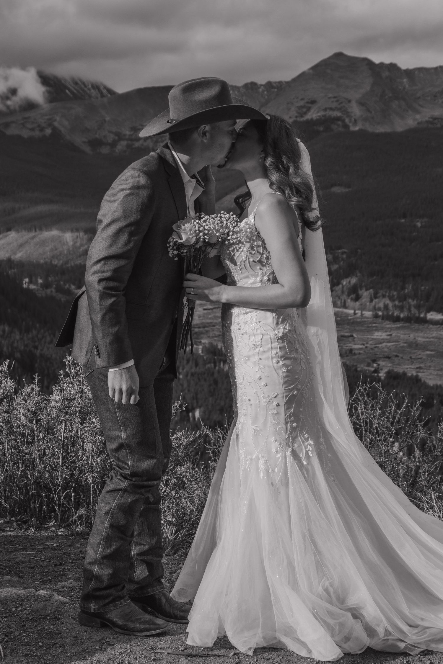 A romantic black and white wedding portrait with mountains in the background.