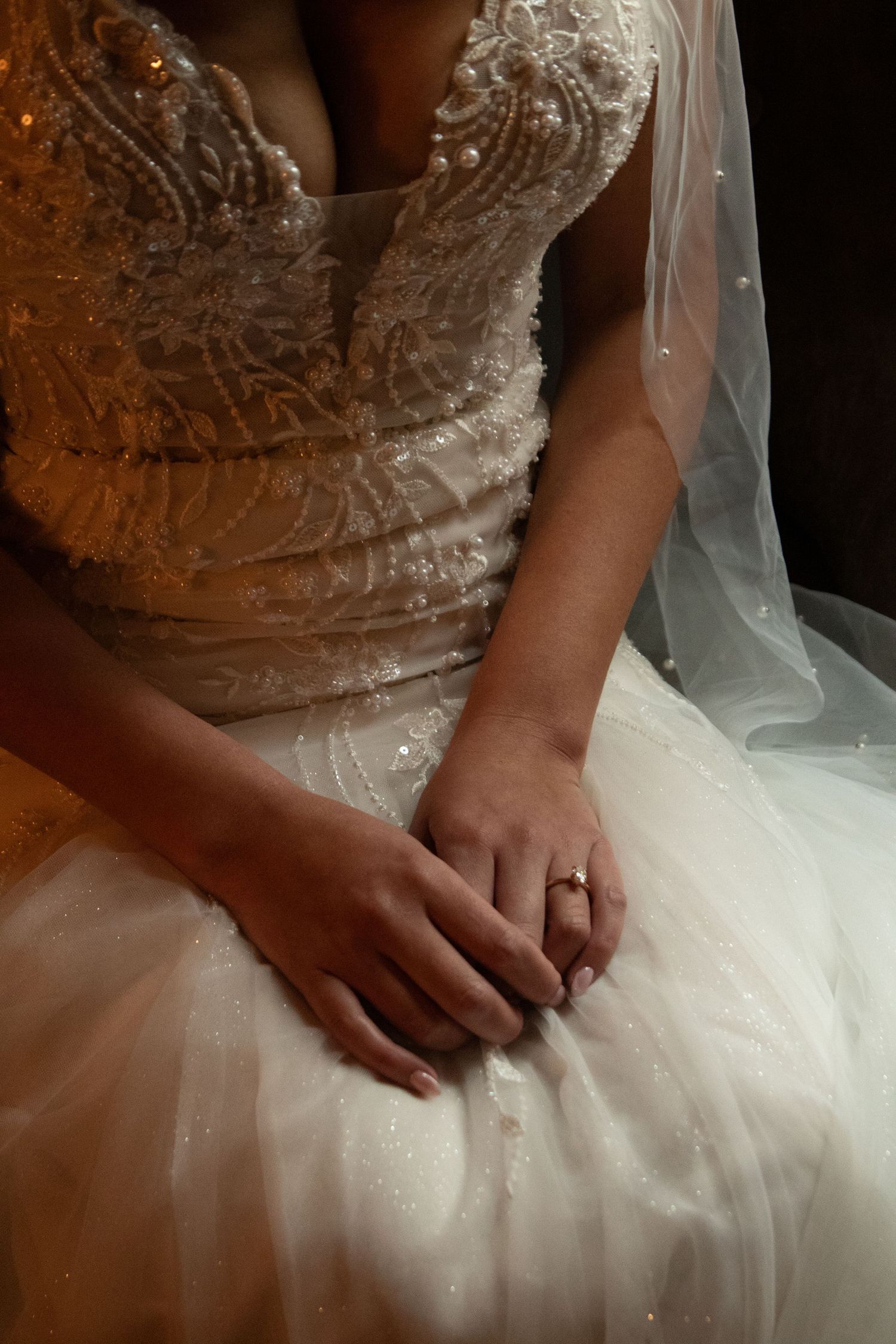 Close-up detail of an intricate lace wedding dress with veil and ring.