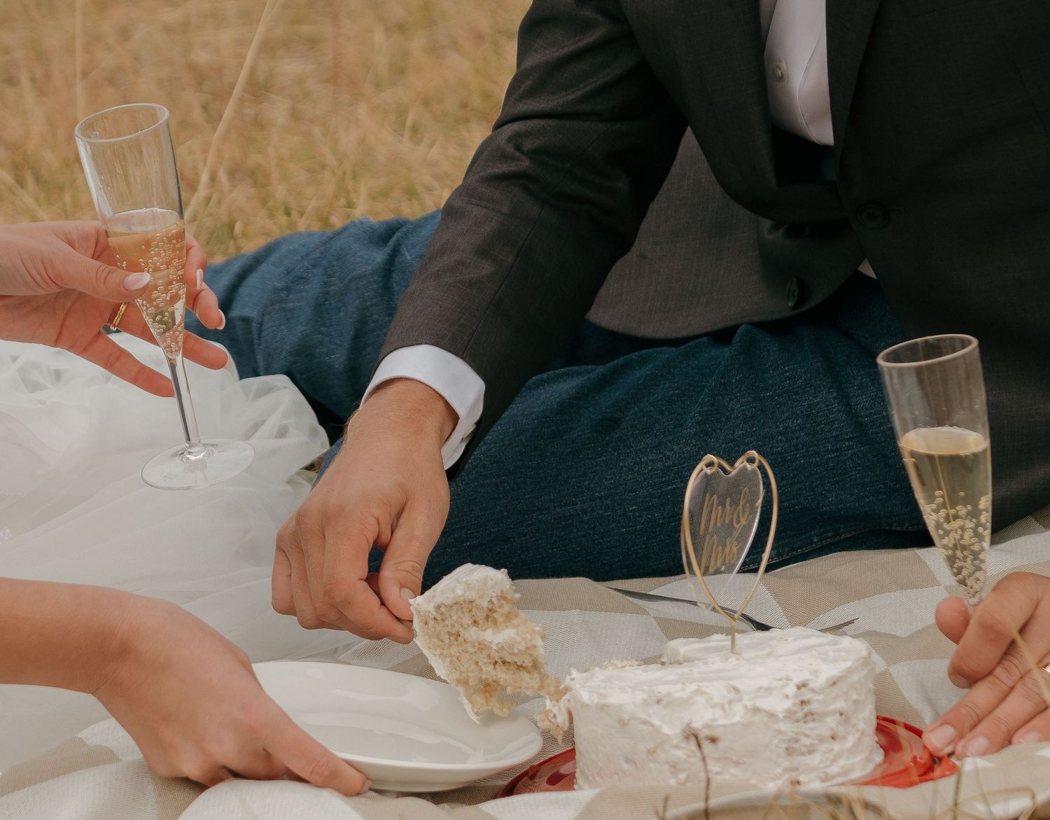 Wedding couple sharing cake and champagne during an intimate outdoor reception.