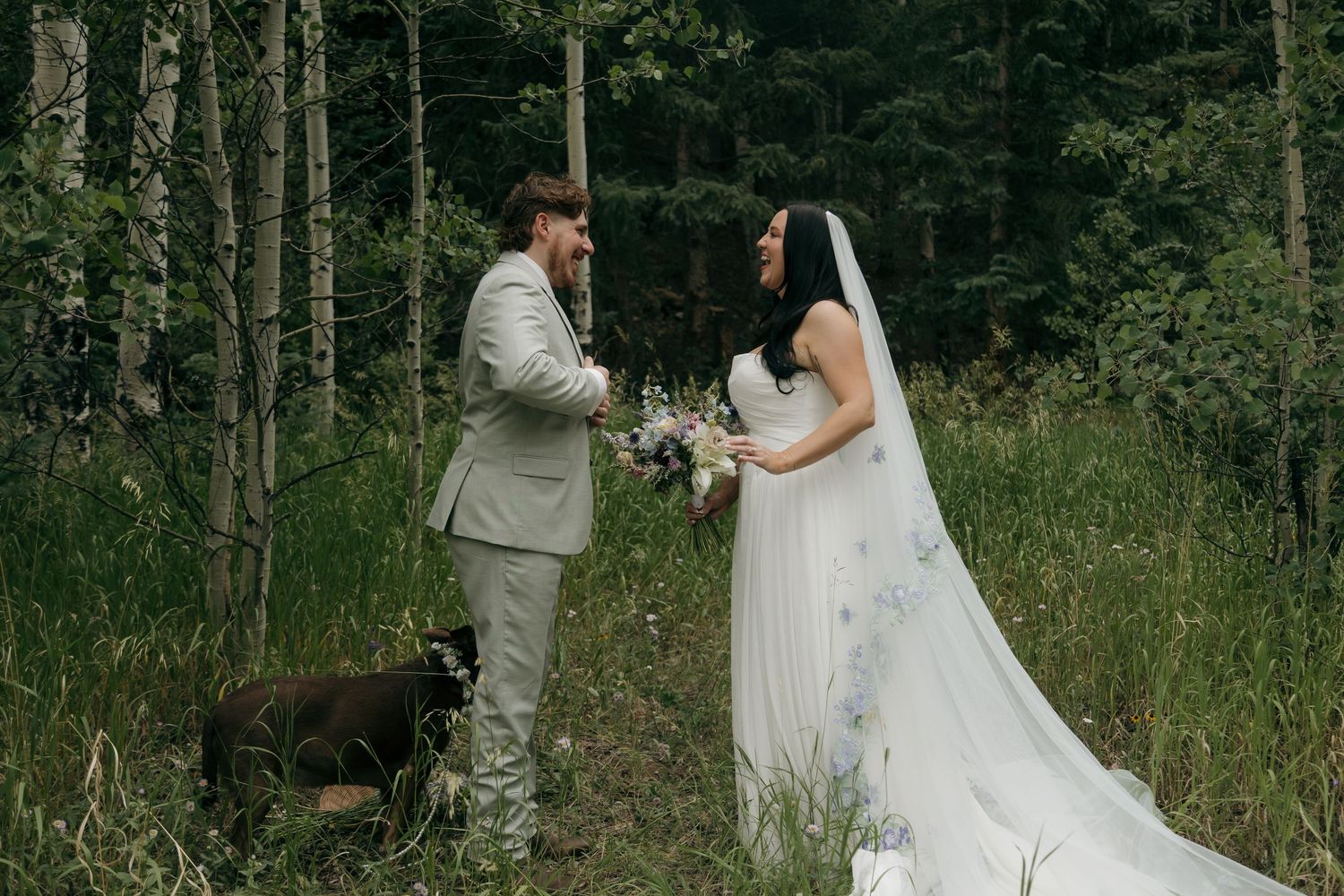 Bride and groom exchange vows in a lush forest clearing, bride holding a wildflower bouquet in a flowing white gown.