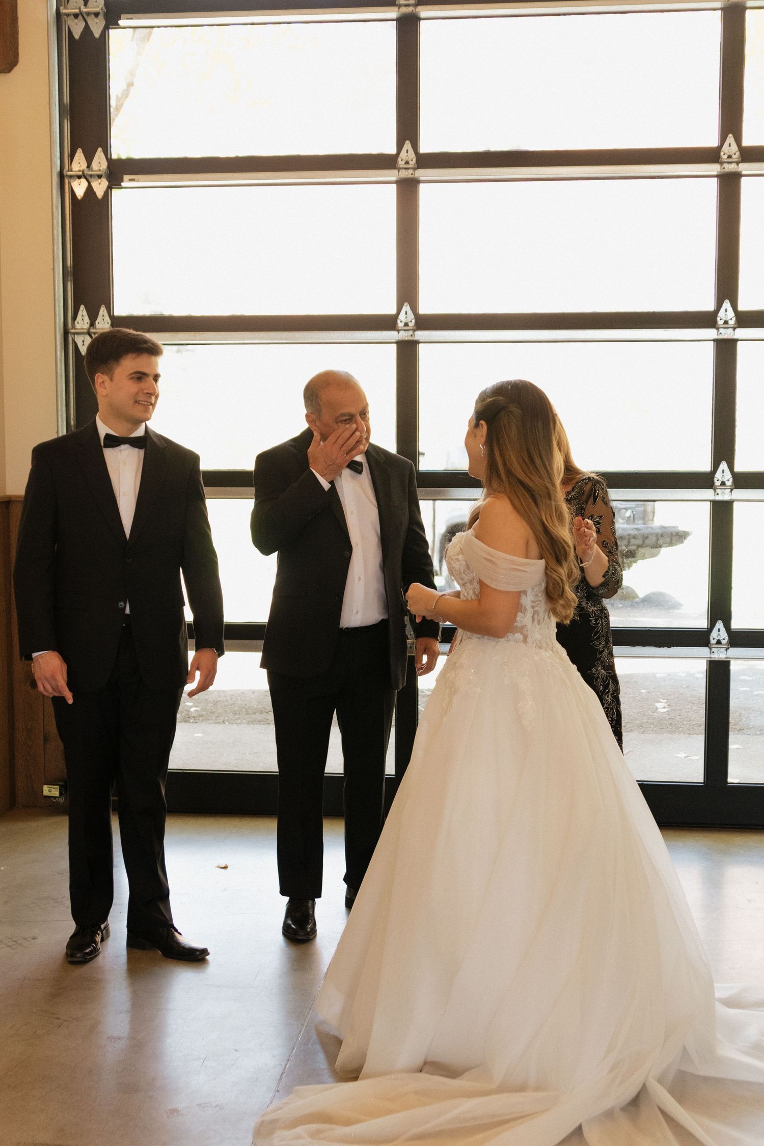 A bride in a flowing white ballgown twirls on a dance floor with guests in formal attire.