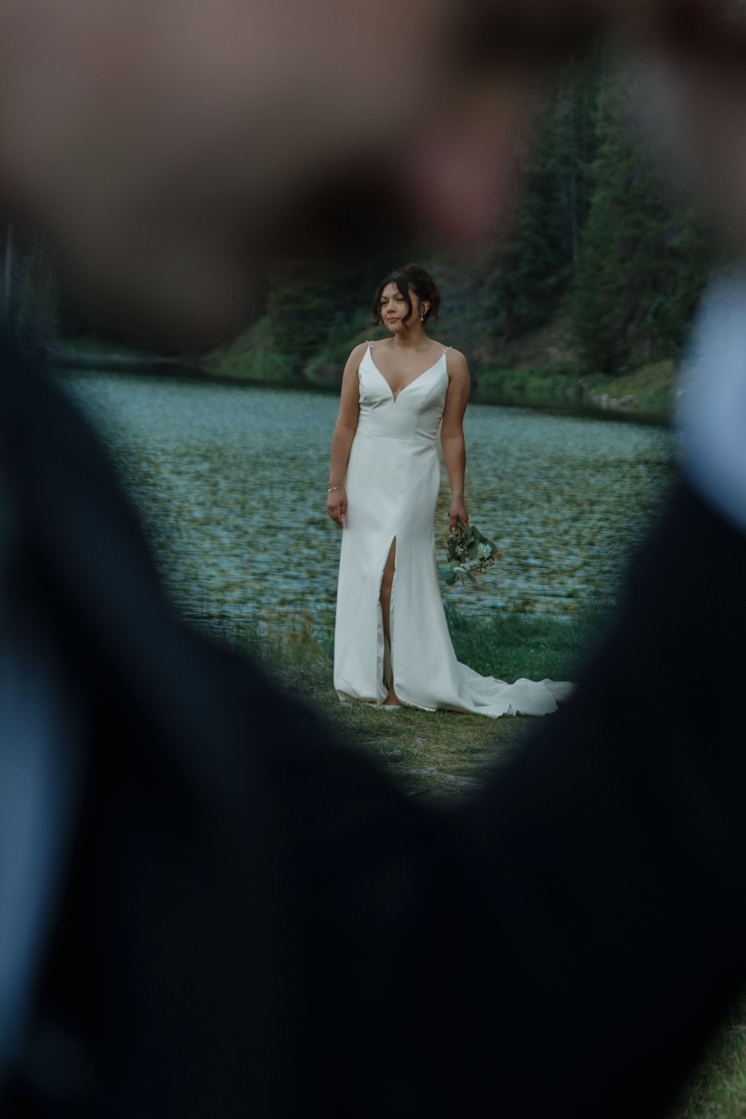 A dreamy wedding photo with the bride in focus against a blurred mountain landscape.