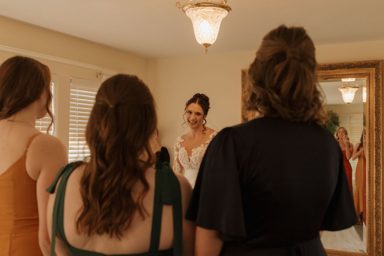 Soft lighting illuminates a room as people gather during wedding preparations.