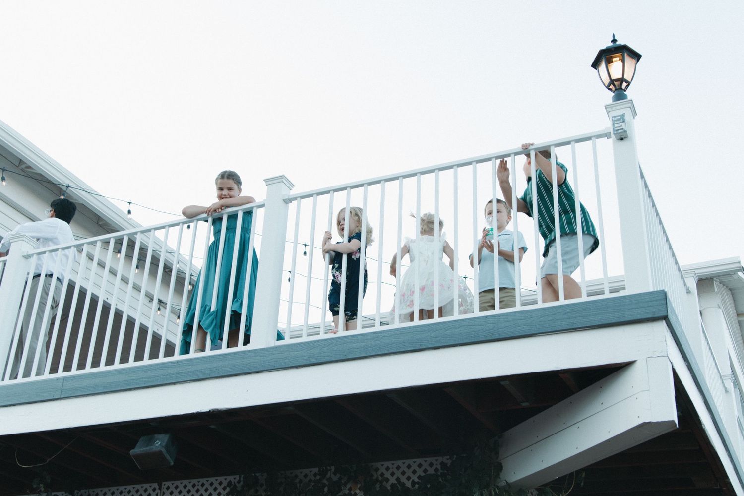 Wedding guests watching from a white balcony railing overlooking the celebration.