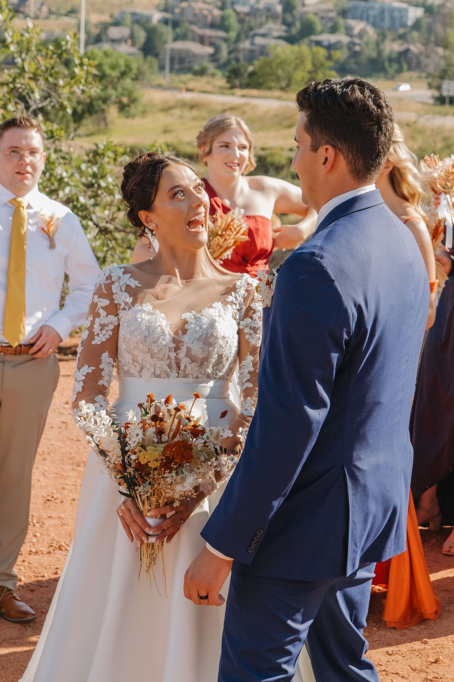 Wedding party celebrating with drinks on rustic outdoor terrace with mountain views.