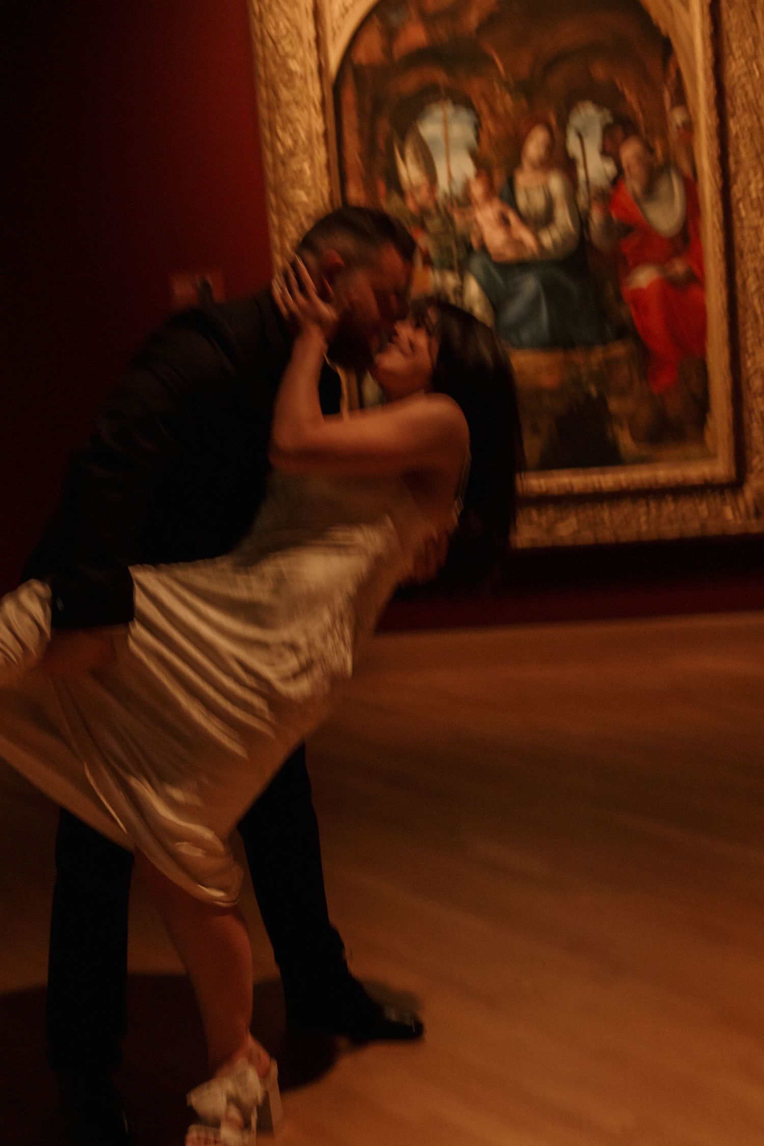 A romantic dance scene unfolds in front of classical artwork in an elegant gallery setting.