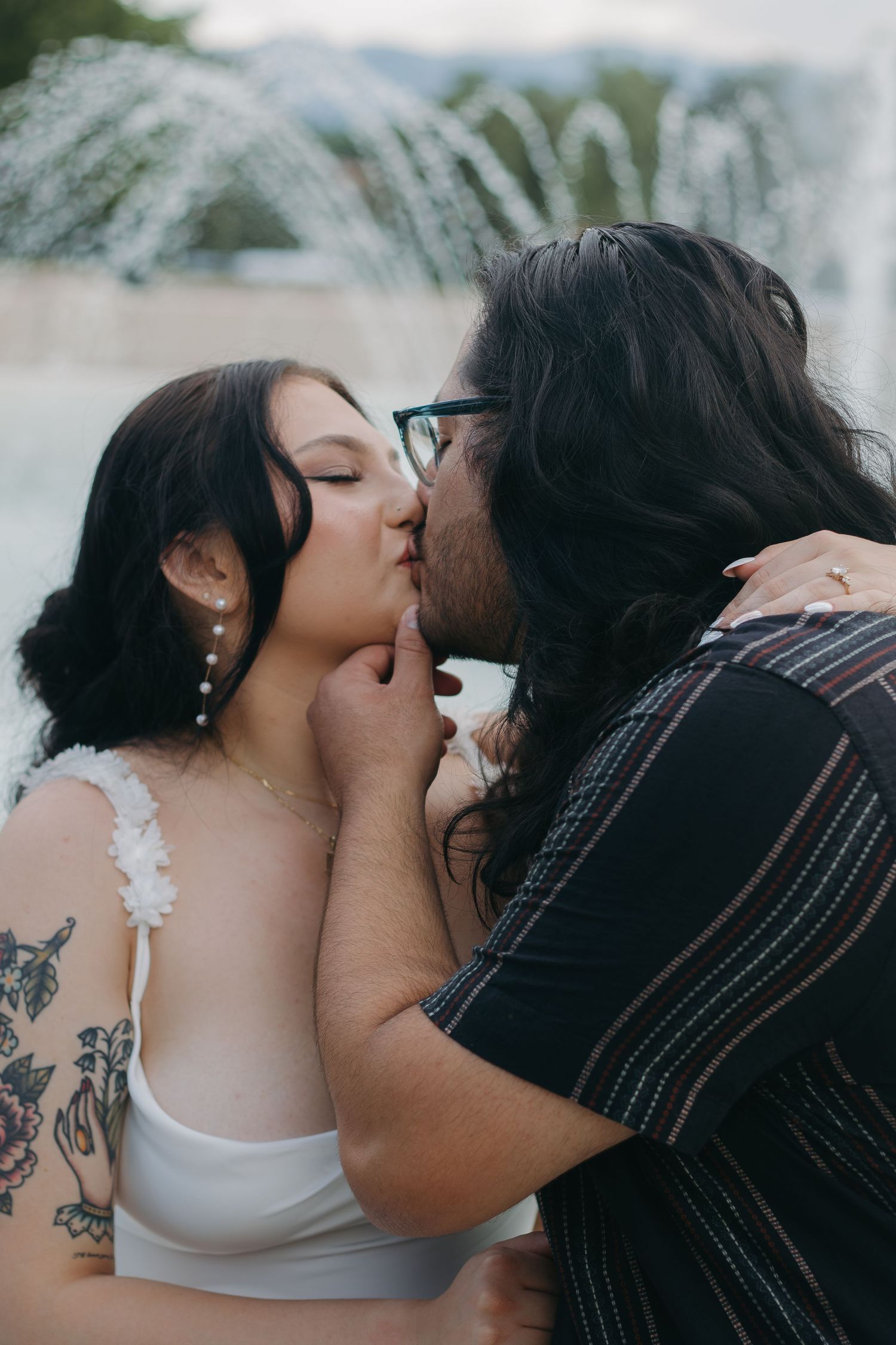 Tender moment captured between a couple sharing an intimate kiss outdoors.