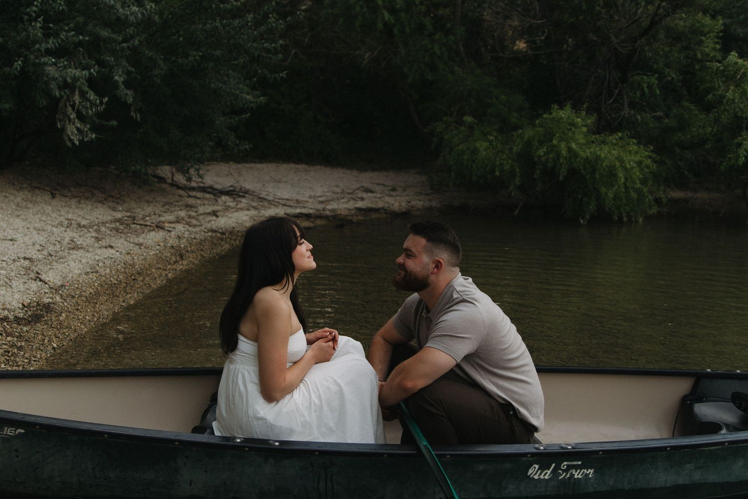 Couple enjoys peaceful moments in canoe against mountainous backdrop.
