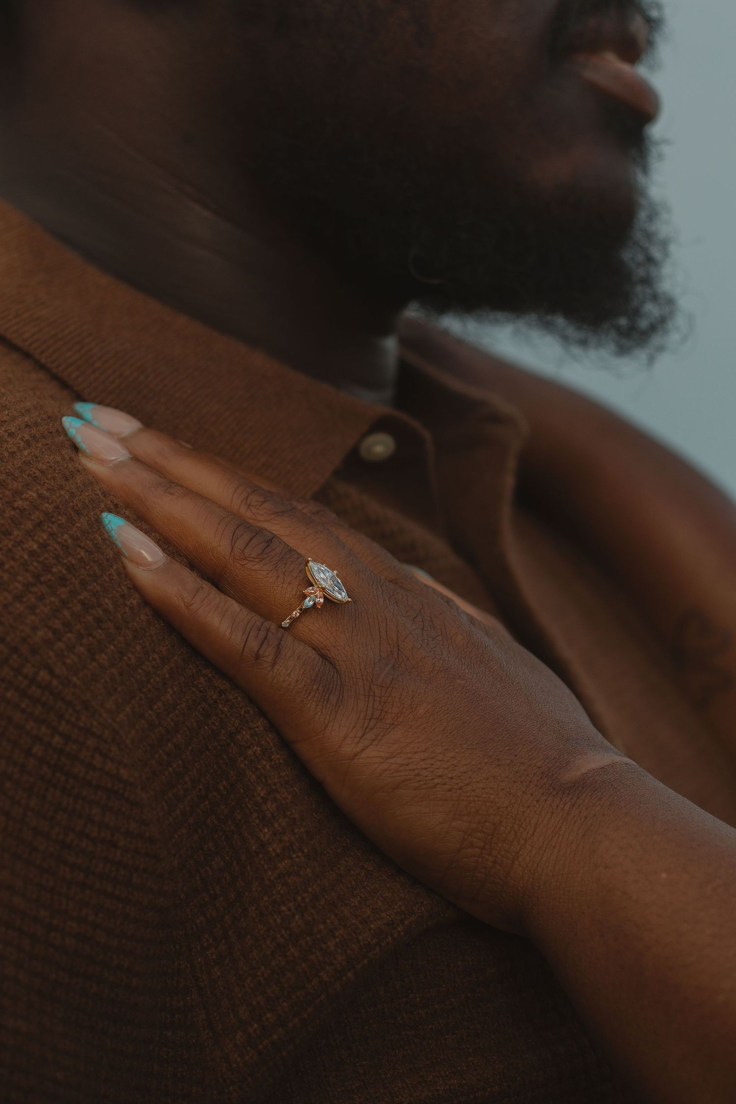 Close-up shots of a sparkling engagement ring on a hand against a brown textured background.