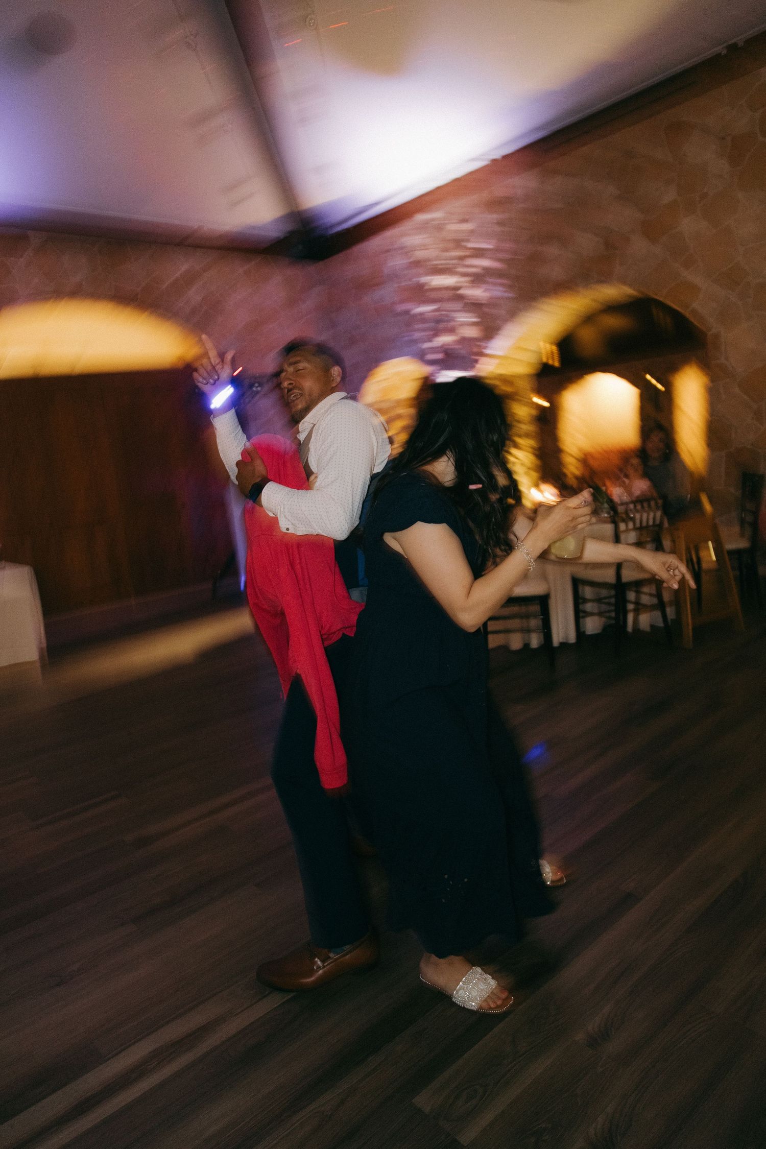 Motion-blurred photo of guests dancing energetically on the dance floor at a wedding reception.