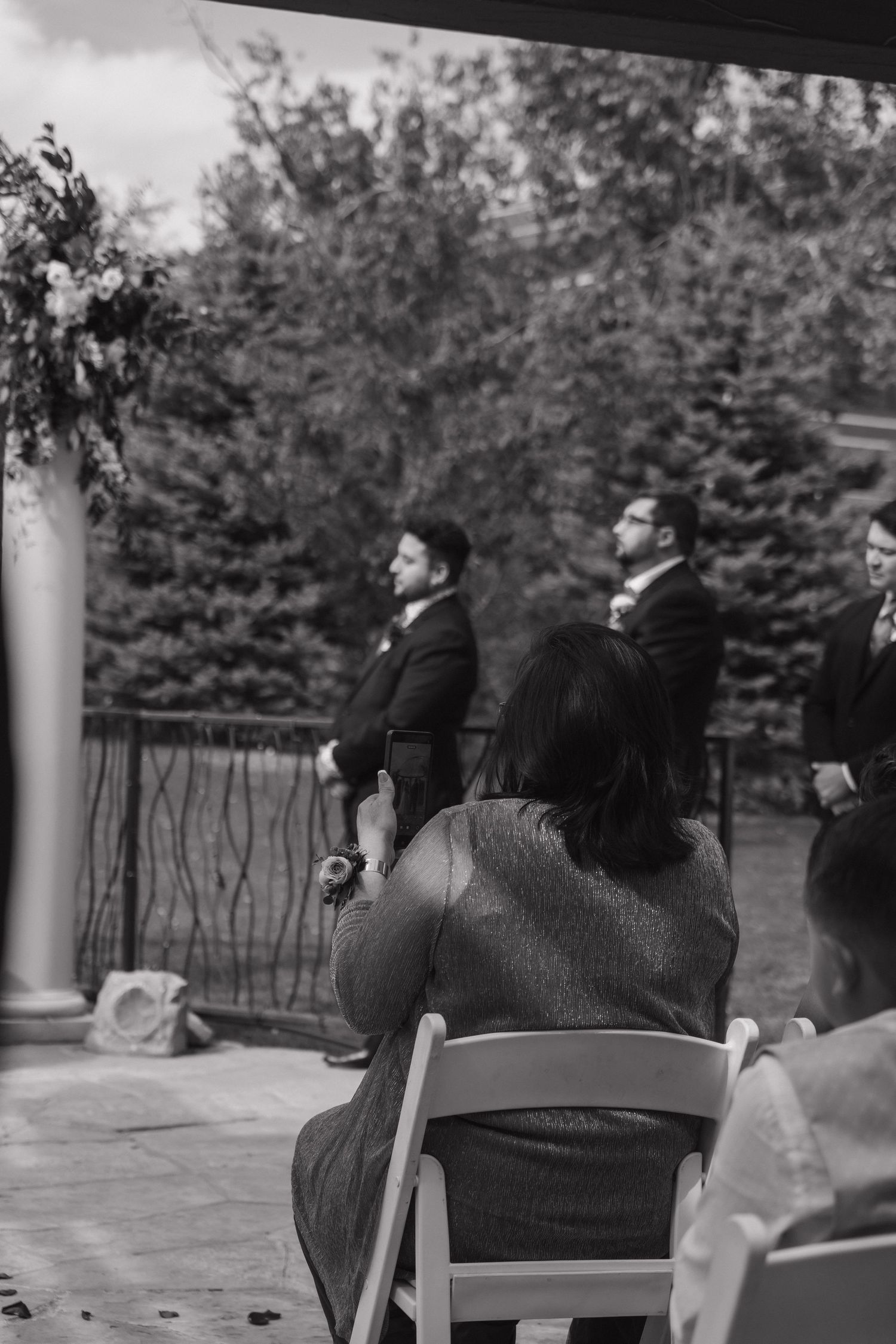 Black and white photo of groomsmen standing at altar while wedding guests watch the ceremony.