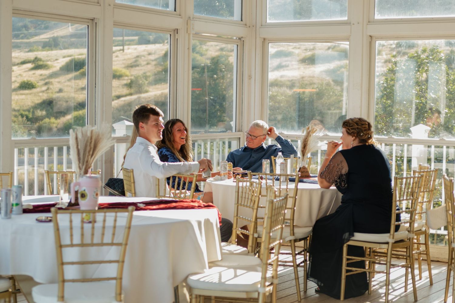 Elegant wedding reception venue with chiavari chairs and mountain views through windows.