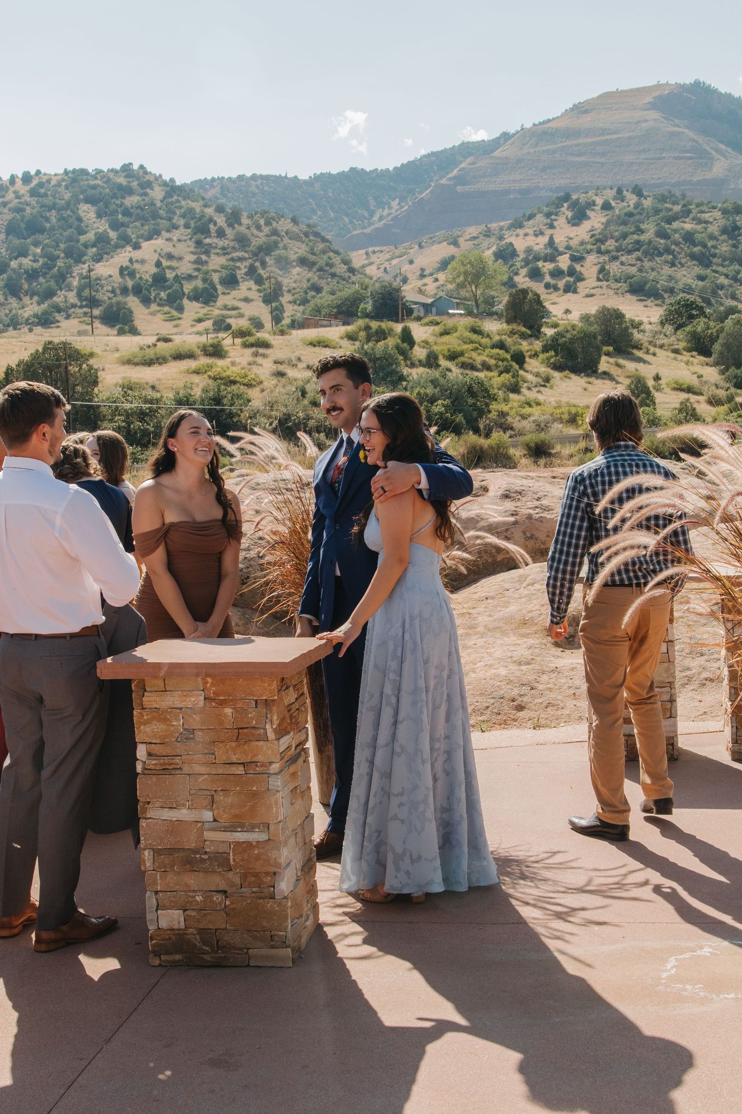Wedding guests mingle and socialize on an outdoor terrace with mountain views in the background.