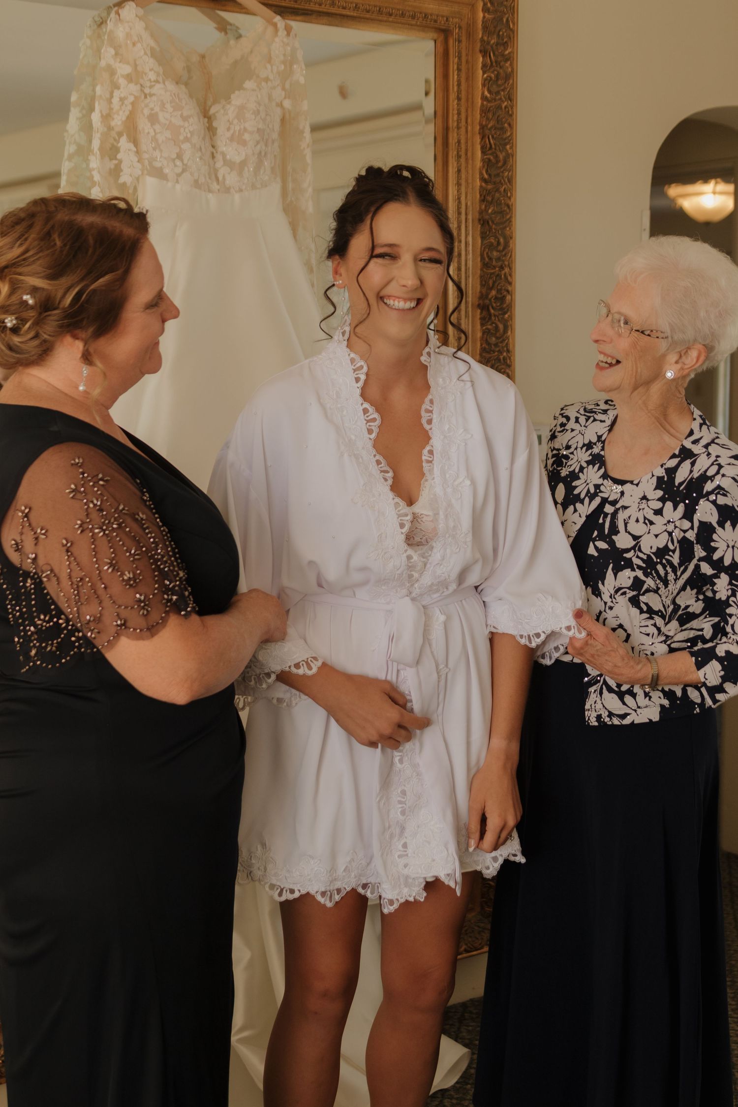 Three generations share laughter during wedding preparations in an elegantly decorated room.