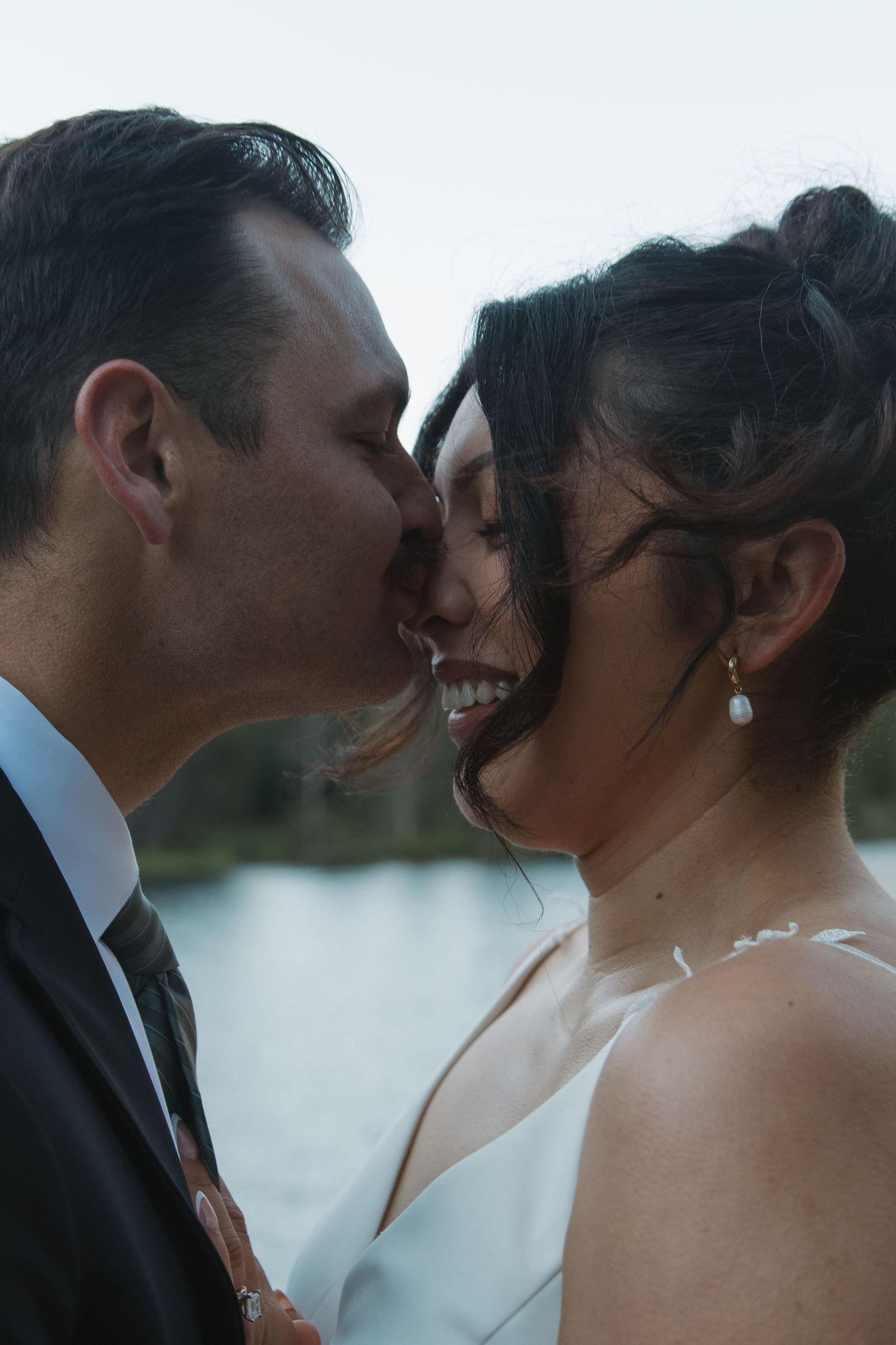 Intimate close-up moments between newlyweds during golden hour by the lake.