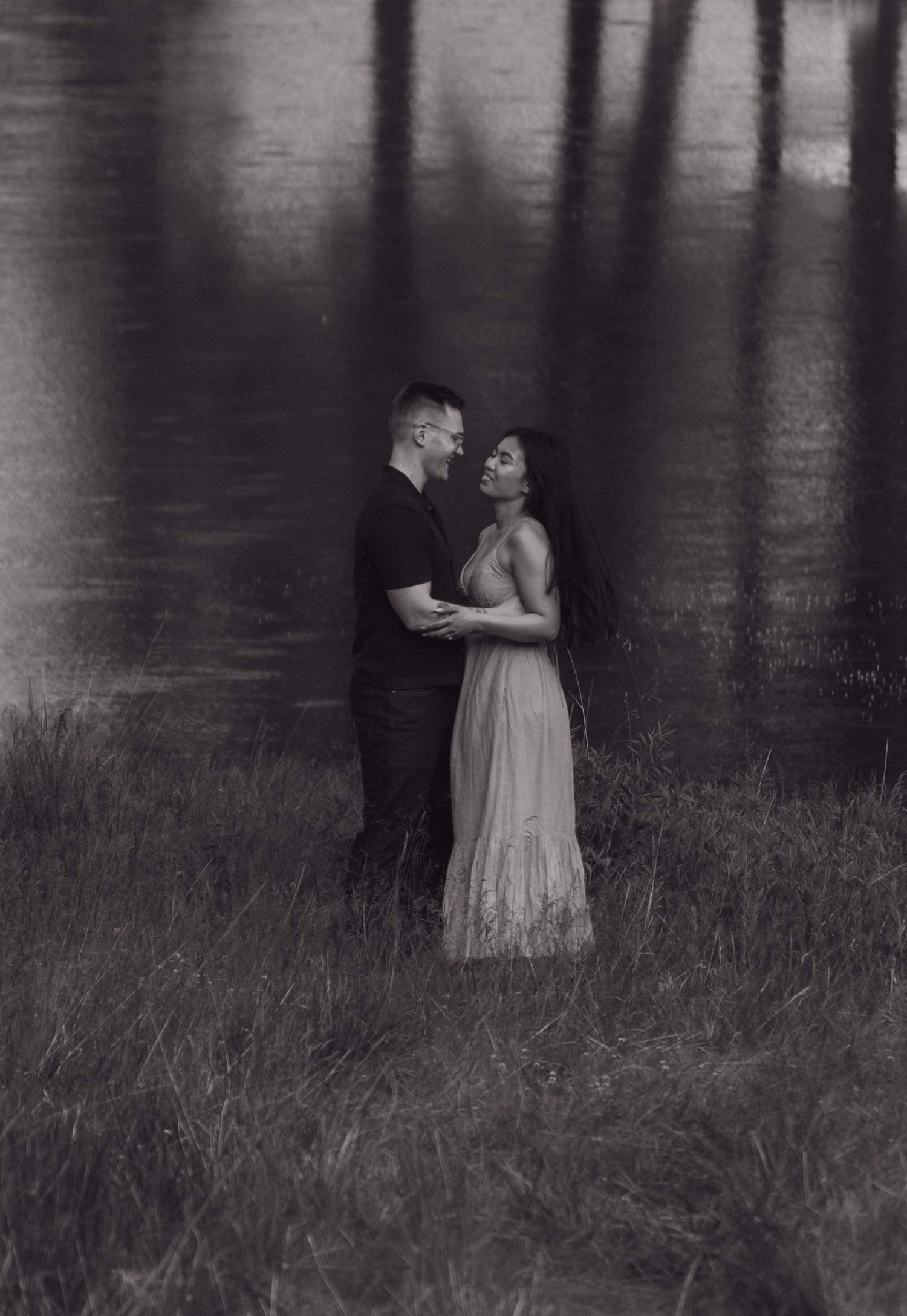 Black and white romantic portrait with moody lighting near a lake.