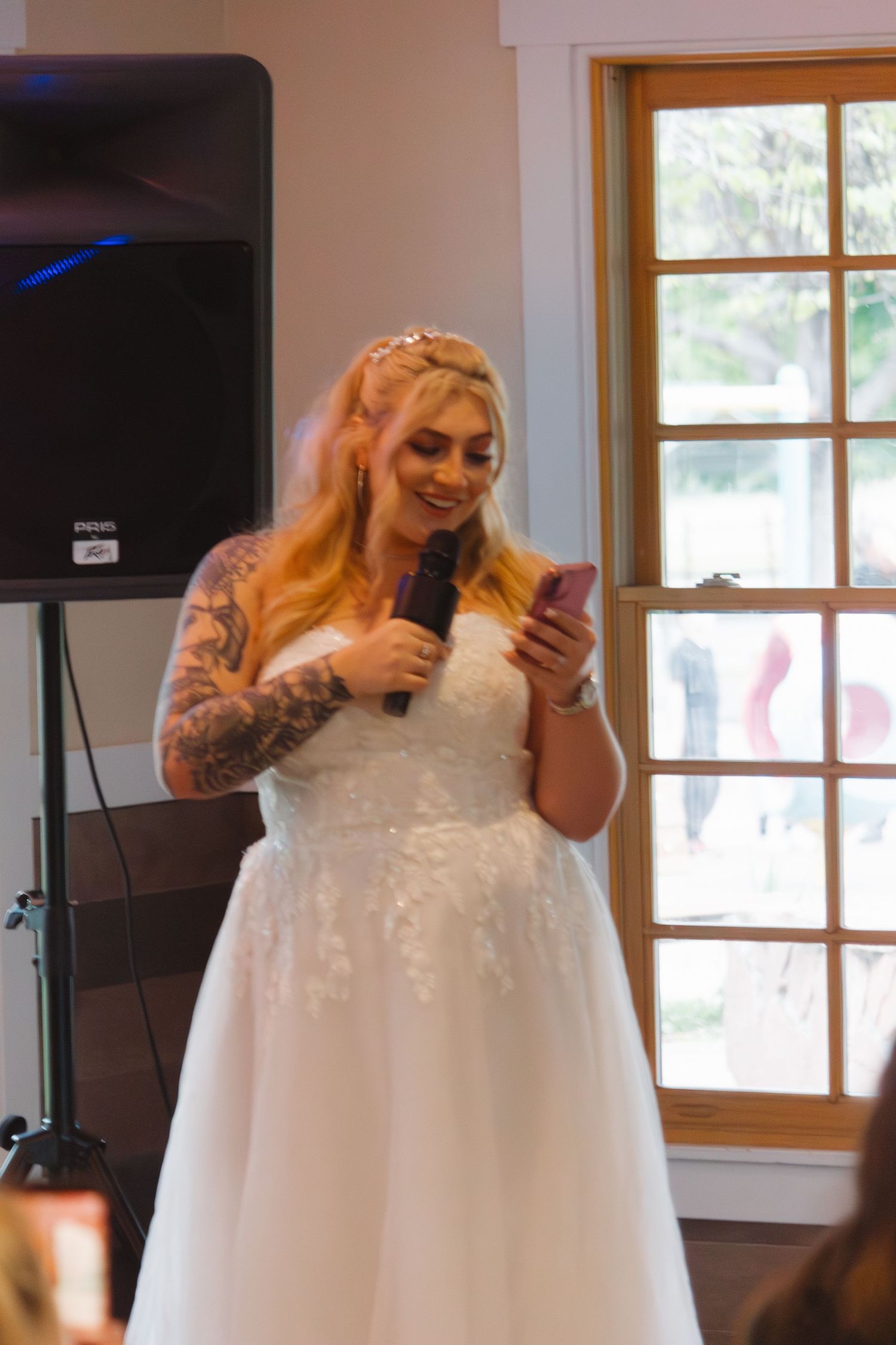 A wedding celebration with the person in white dress holding microphone and phone during reception.