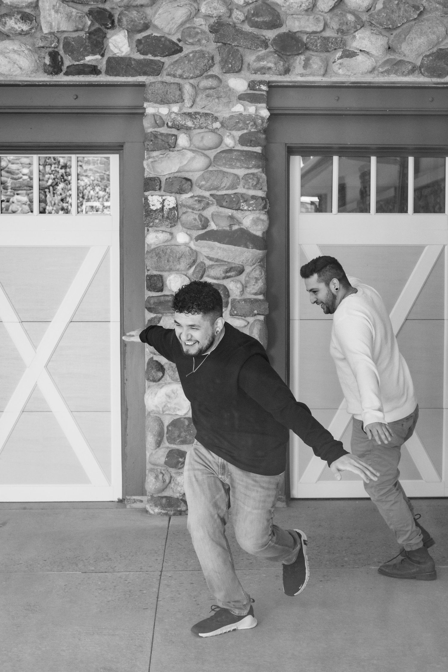 Playful moment captured in black and white against stone wall and garage doors.