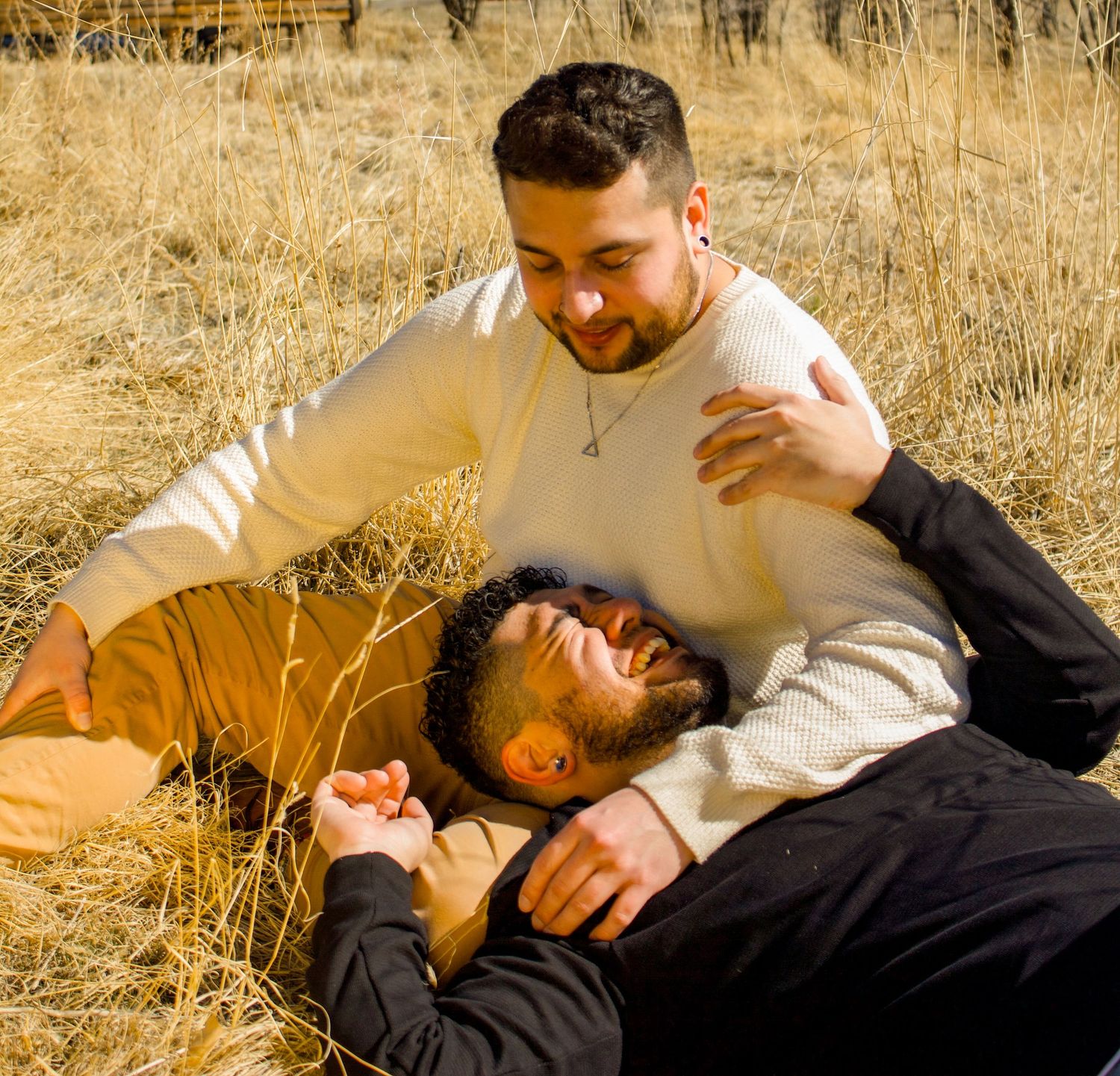 Two figures sitting on grass in golden sunlight with warm autumn tones in background.