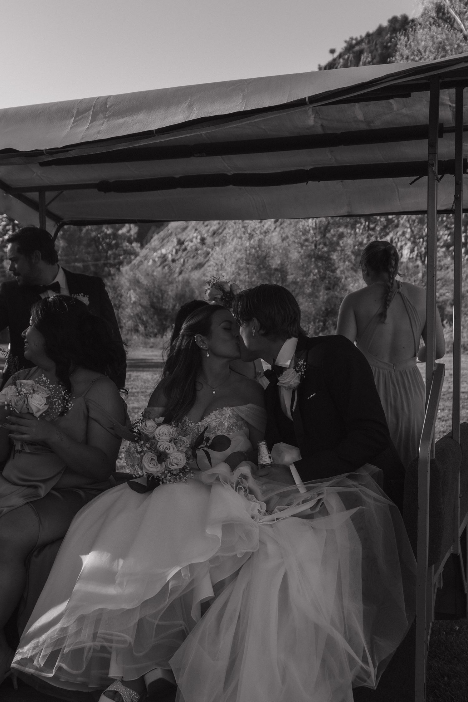 Black and white photo of wedding guests riding in a covered cart or wagon.