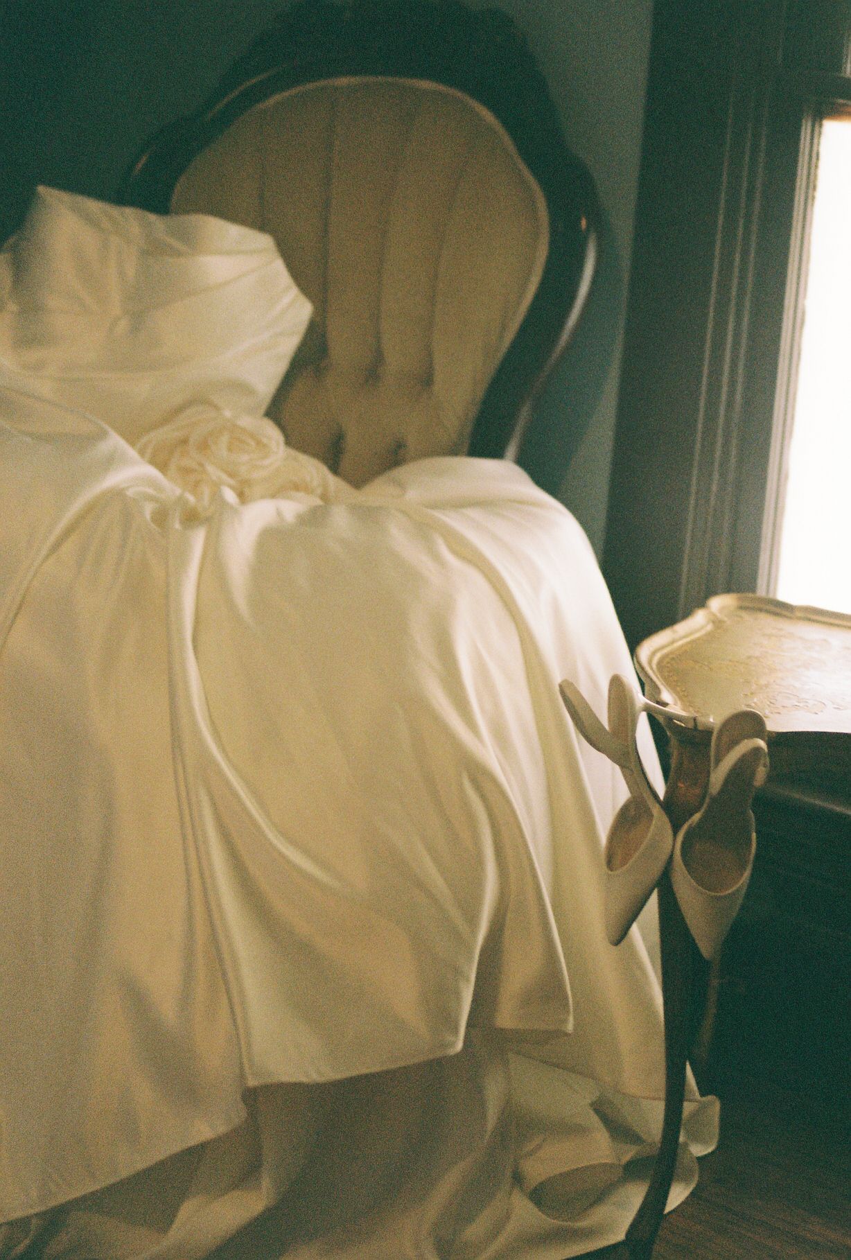 Close-up details of white wedding dress fabric and bow in soft natural light.