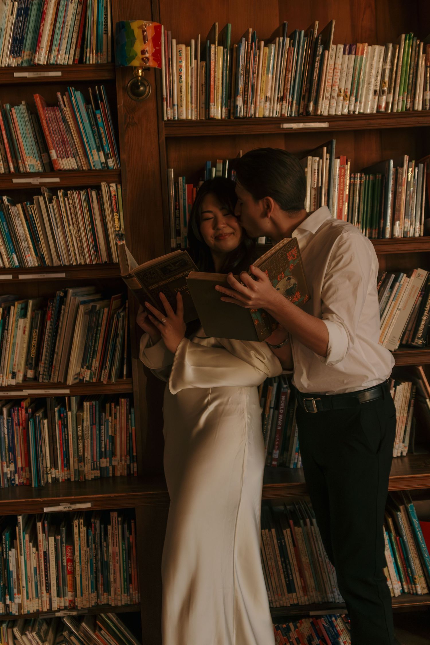 Couple shares intimate moment while reading book together in vintage library setting.