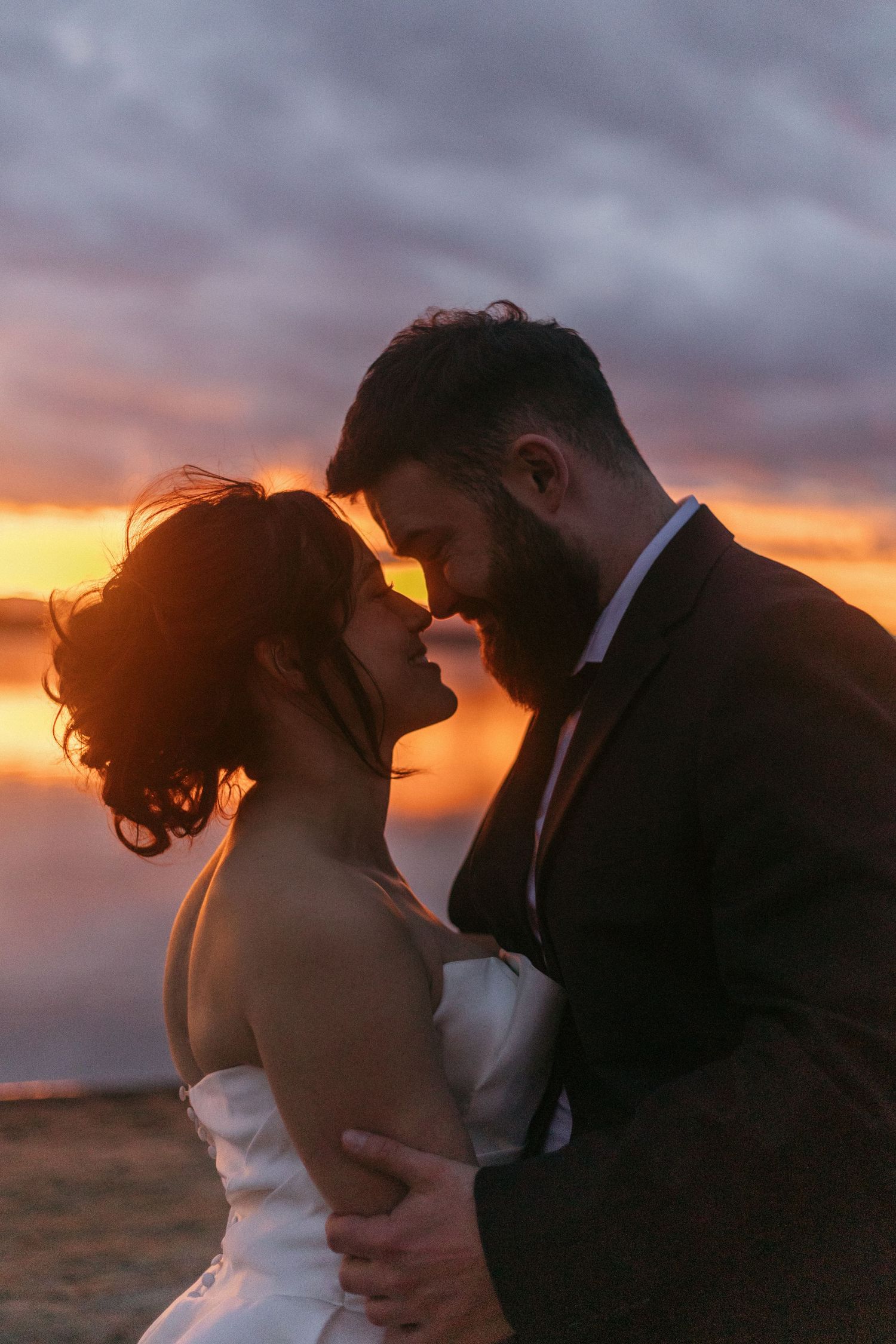 A romantic sunset silhouette shows a couple embracing in a desert landscape with dramatic orange sky.
