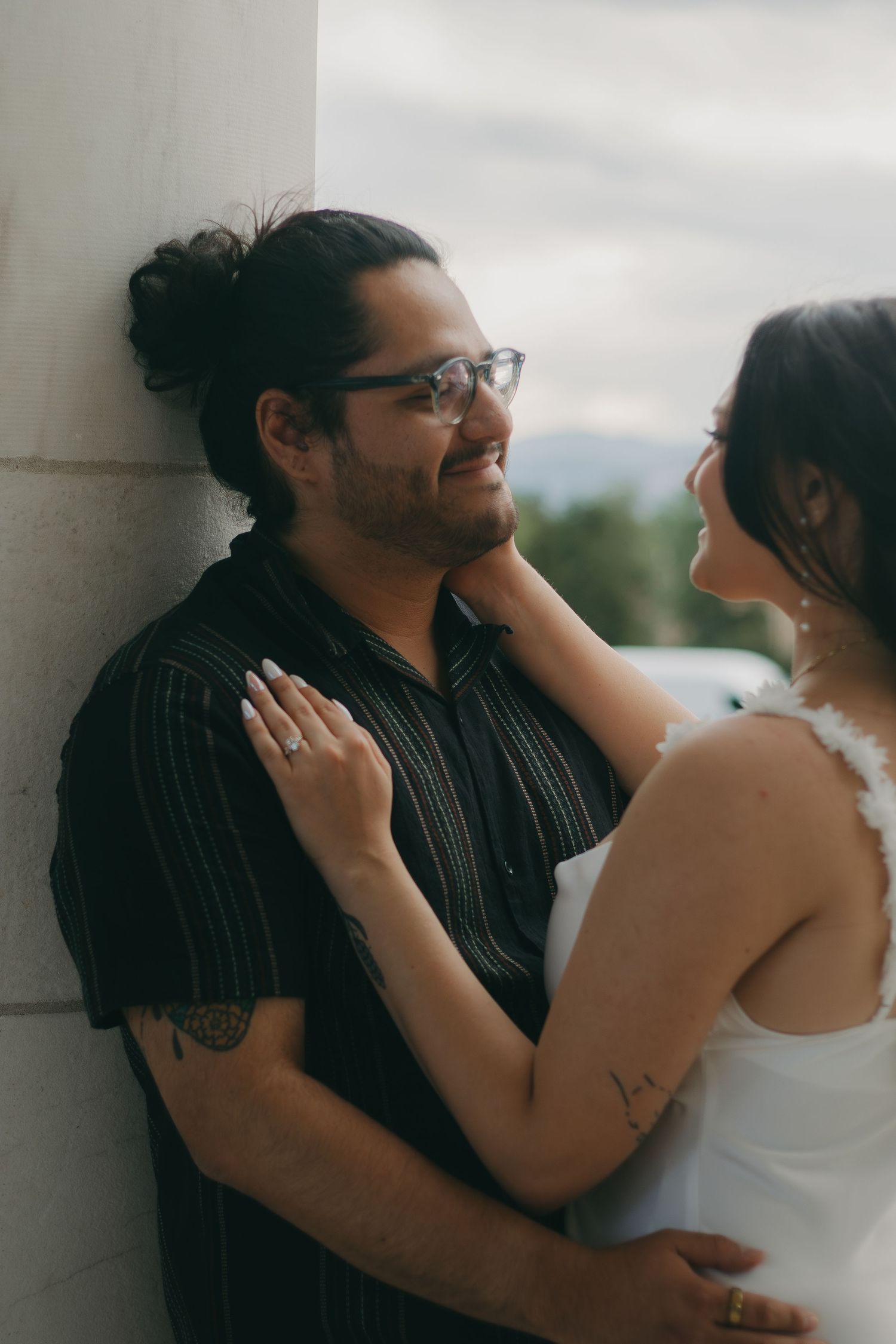 A romantic portrait of a couple sharing a tender moment against a light colored wall.