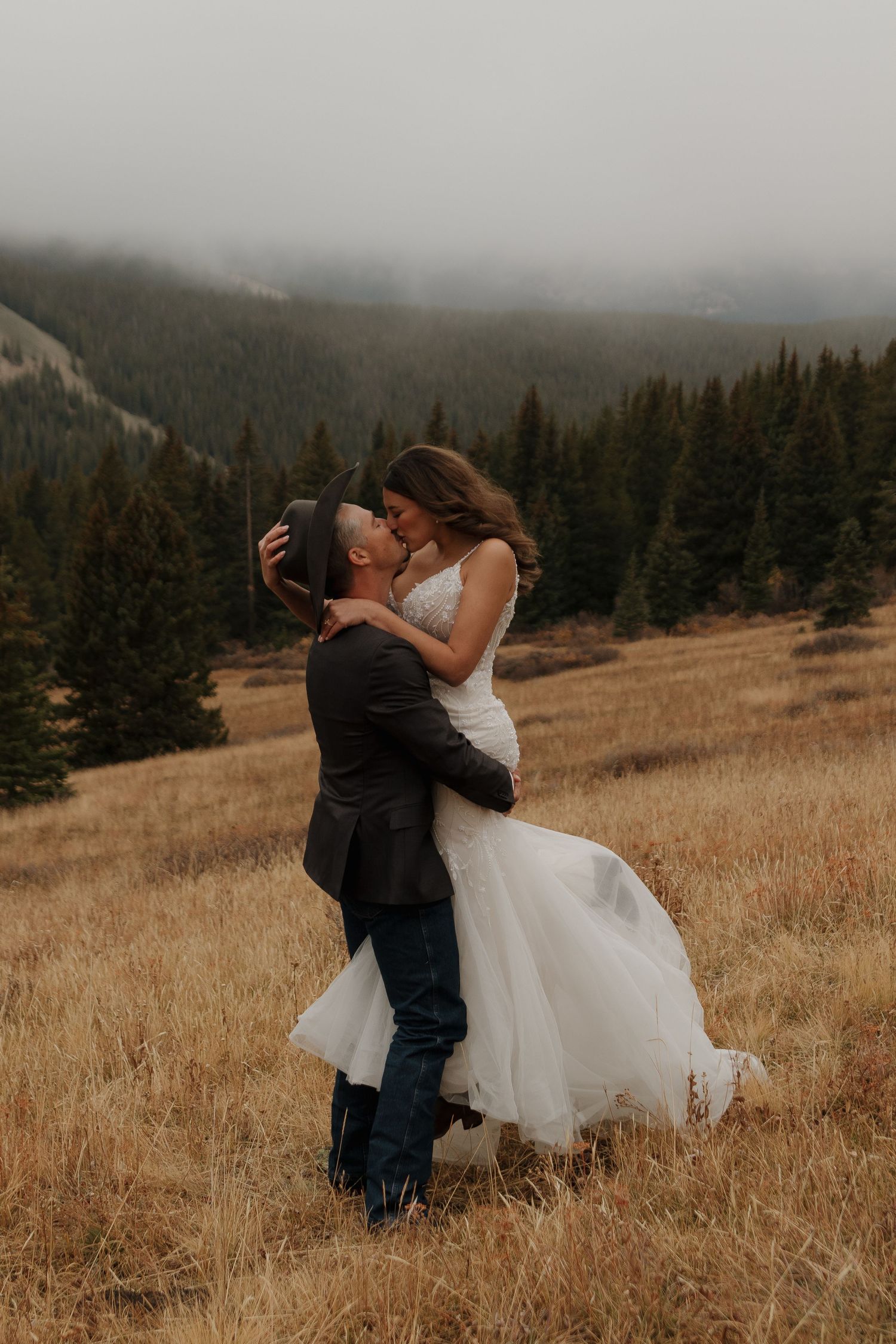 Romantic wedding photos in a mountain meadow with dramatic cloudy skies.