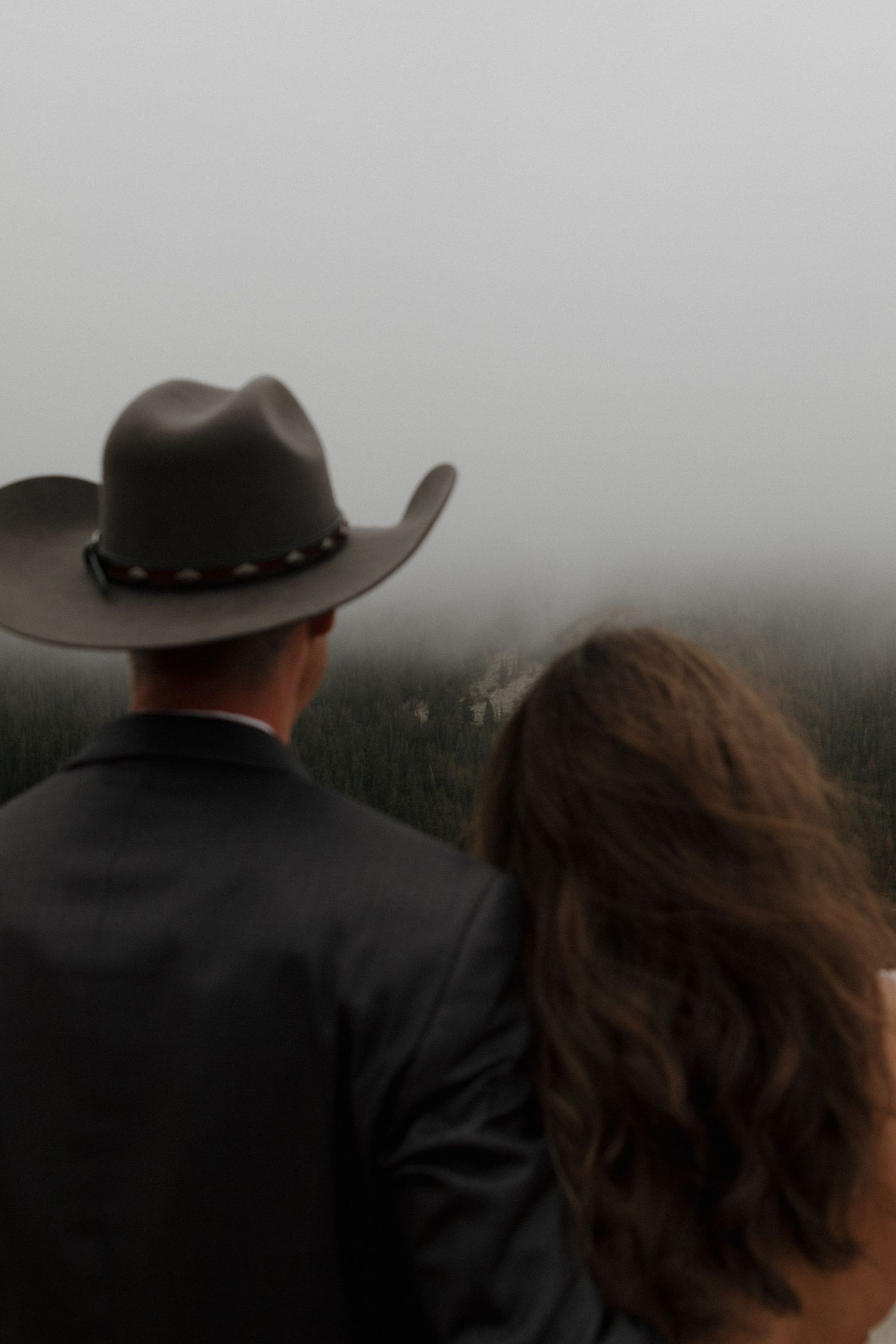 A silhouetted couple stands against a misty mountain backdrop.