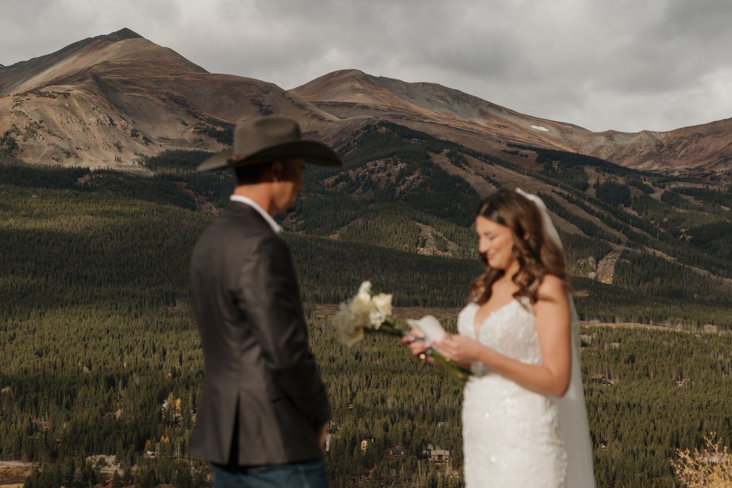A couple exchanges vows during their mountain wedding ceremony with dramatic peaks in the background.