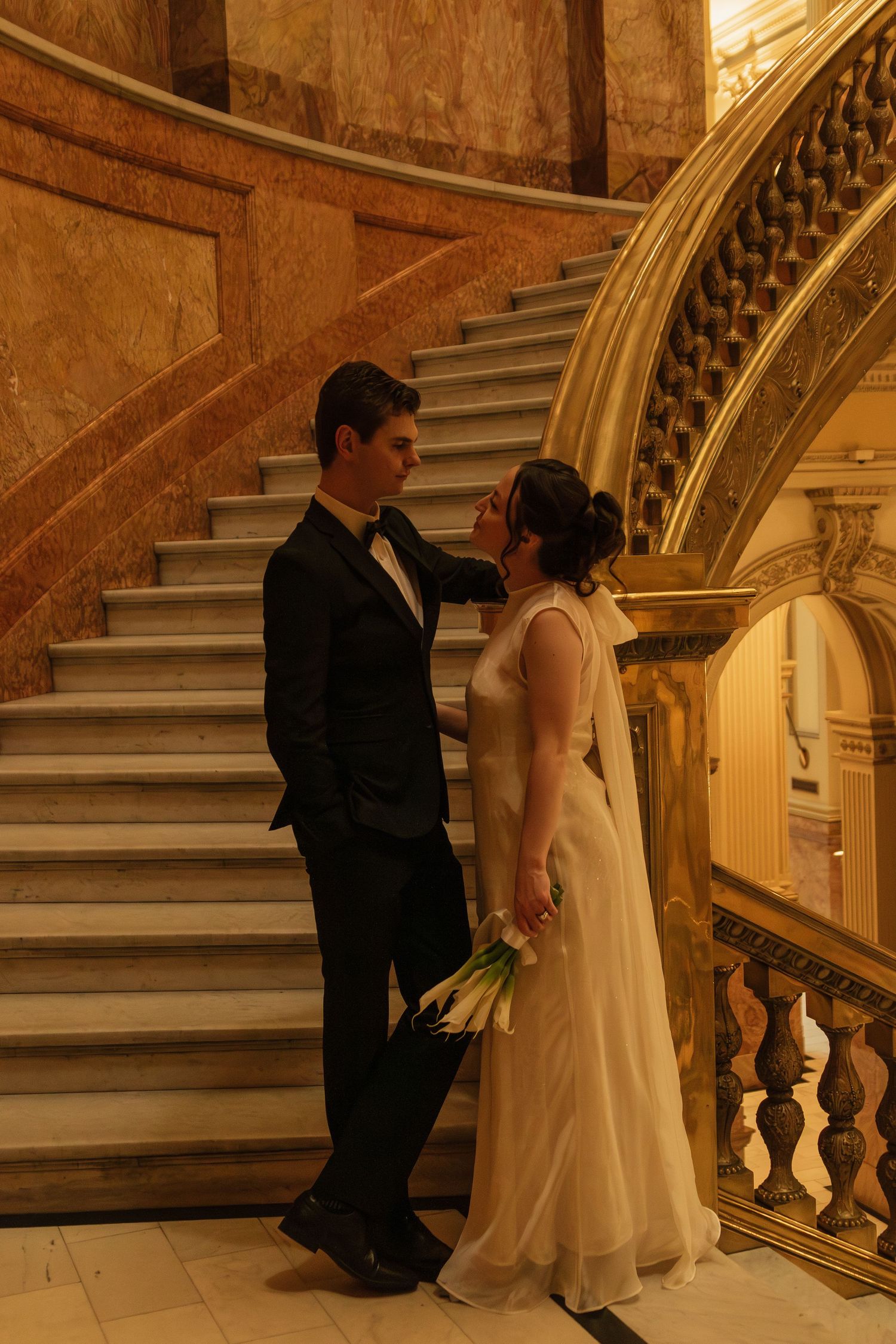 Series of wedding photos on elegant marble staircase with ornate gold railings.
