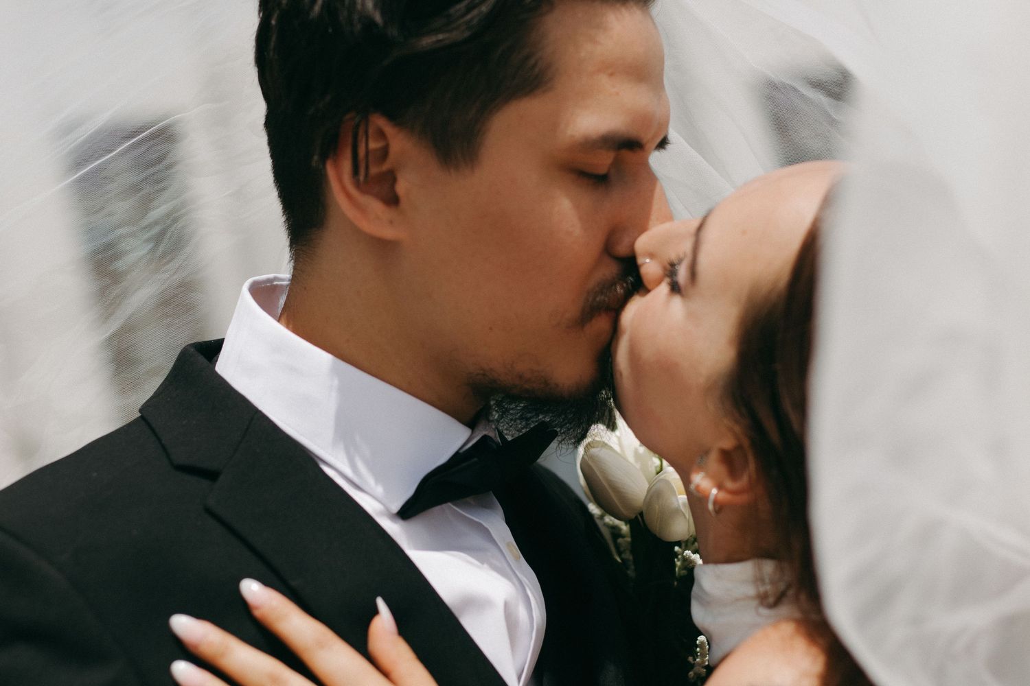 Romantic black and white wedding photos show newlyweds sharing intimate kisses in a collage of four images.